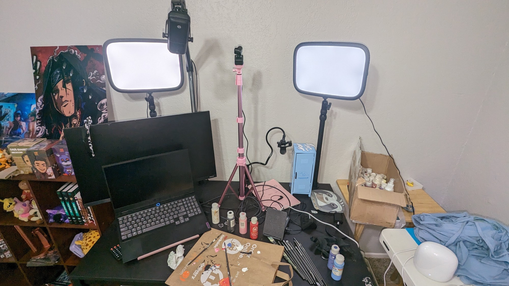 up close of my streaming desk; there is one monitor, a laptop, two el gato key lights, a wavelength from elgato, and lots of paint sprawled across the desk. The laptop is a lenovo legion.