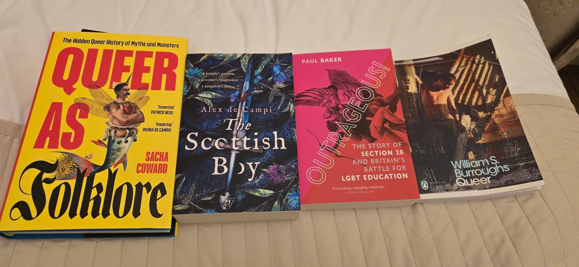 4 books laid out on a beige bedspread: Queer as Folklore by Sacha Coward (hardback), The Scottish Boy by Alex de Vampire, Outrageous! by Paul Baker and Queer by William S. Burroughs.