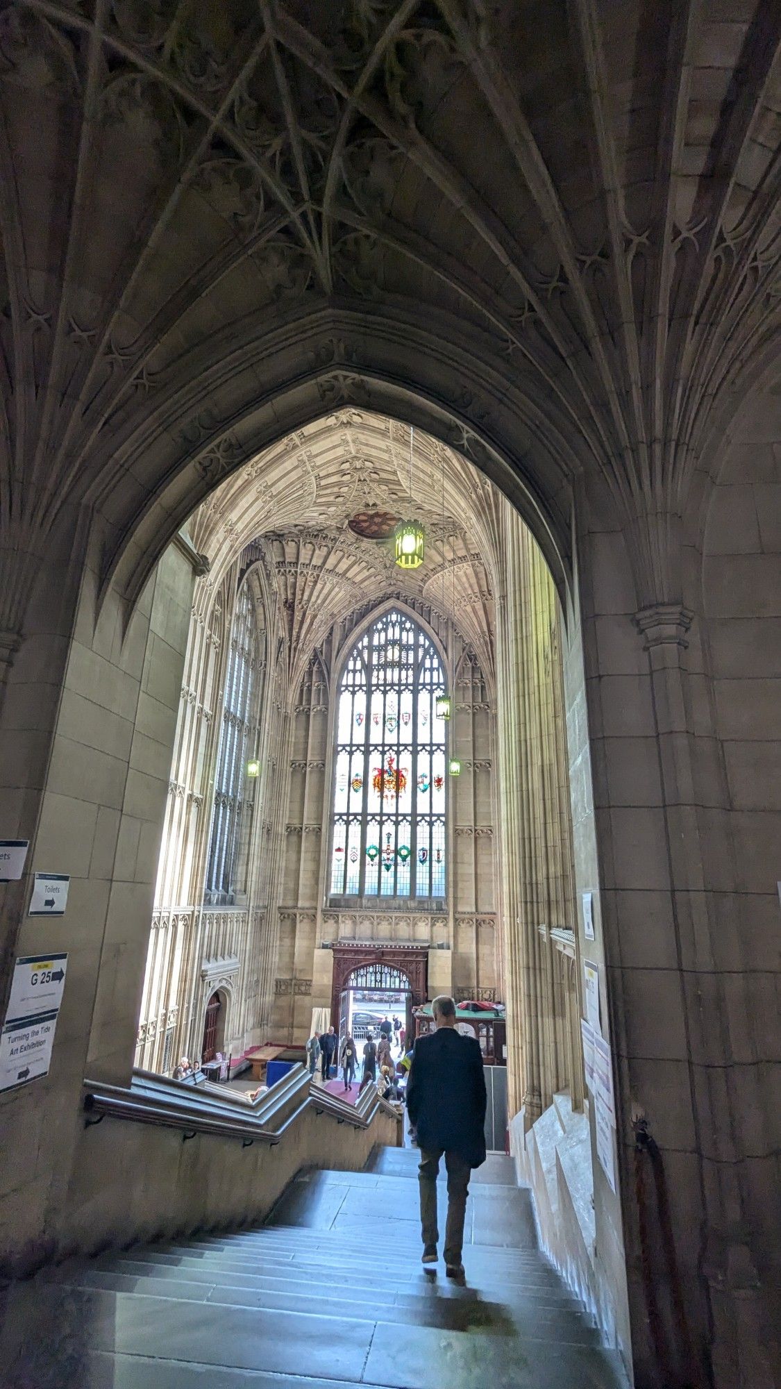 Man walking downstairs seen from behind framed by beautiful gothic arches at Bristol University