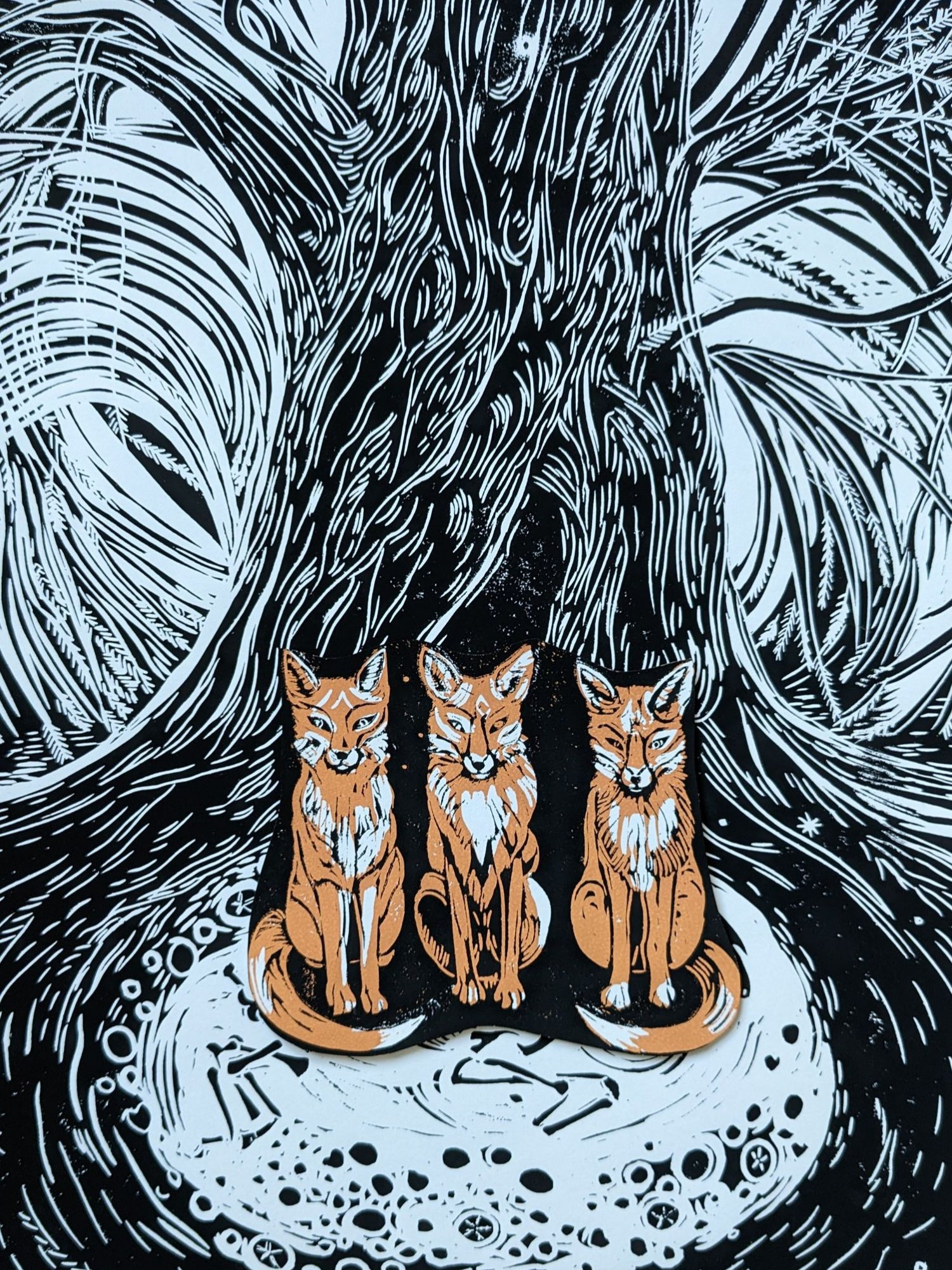 three foxes beneath a yew tree, bones, sea urchin fossils. Linocut, orangebrown, white and black, Maria Strutz