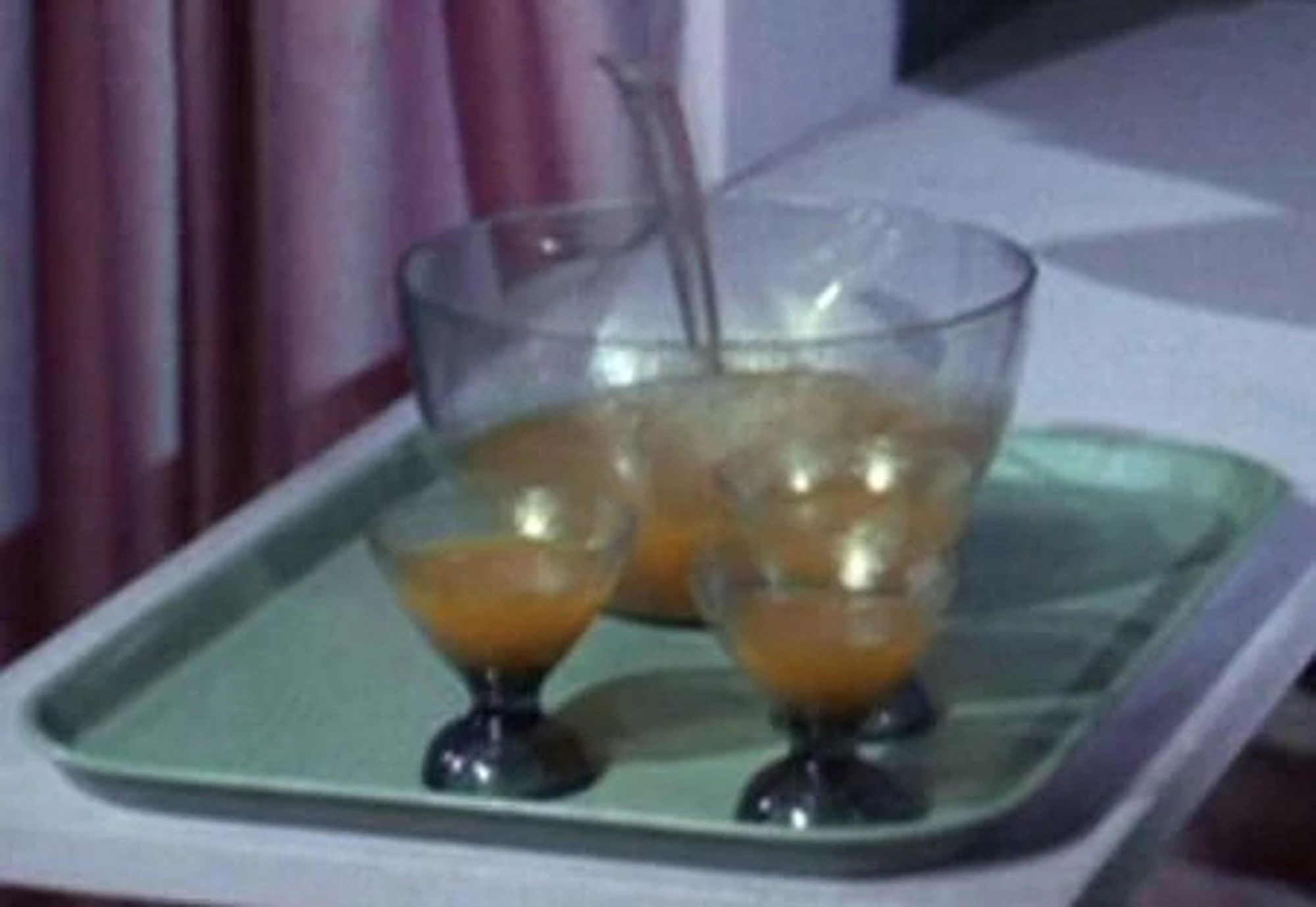 A screenshot from Star Trek featuring a punch bowl full of tranya and three already filled glasses.