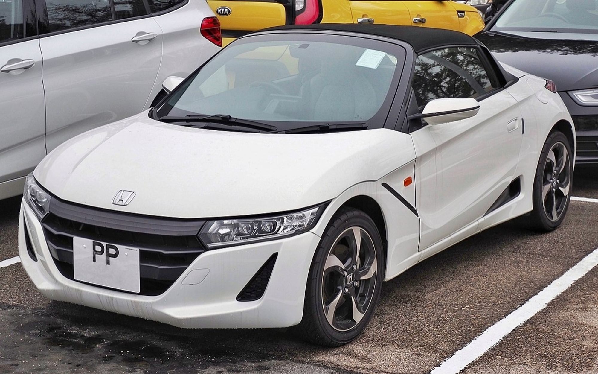 A white Honda S660, a very small mid-engined kei car convertible