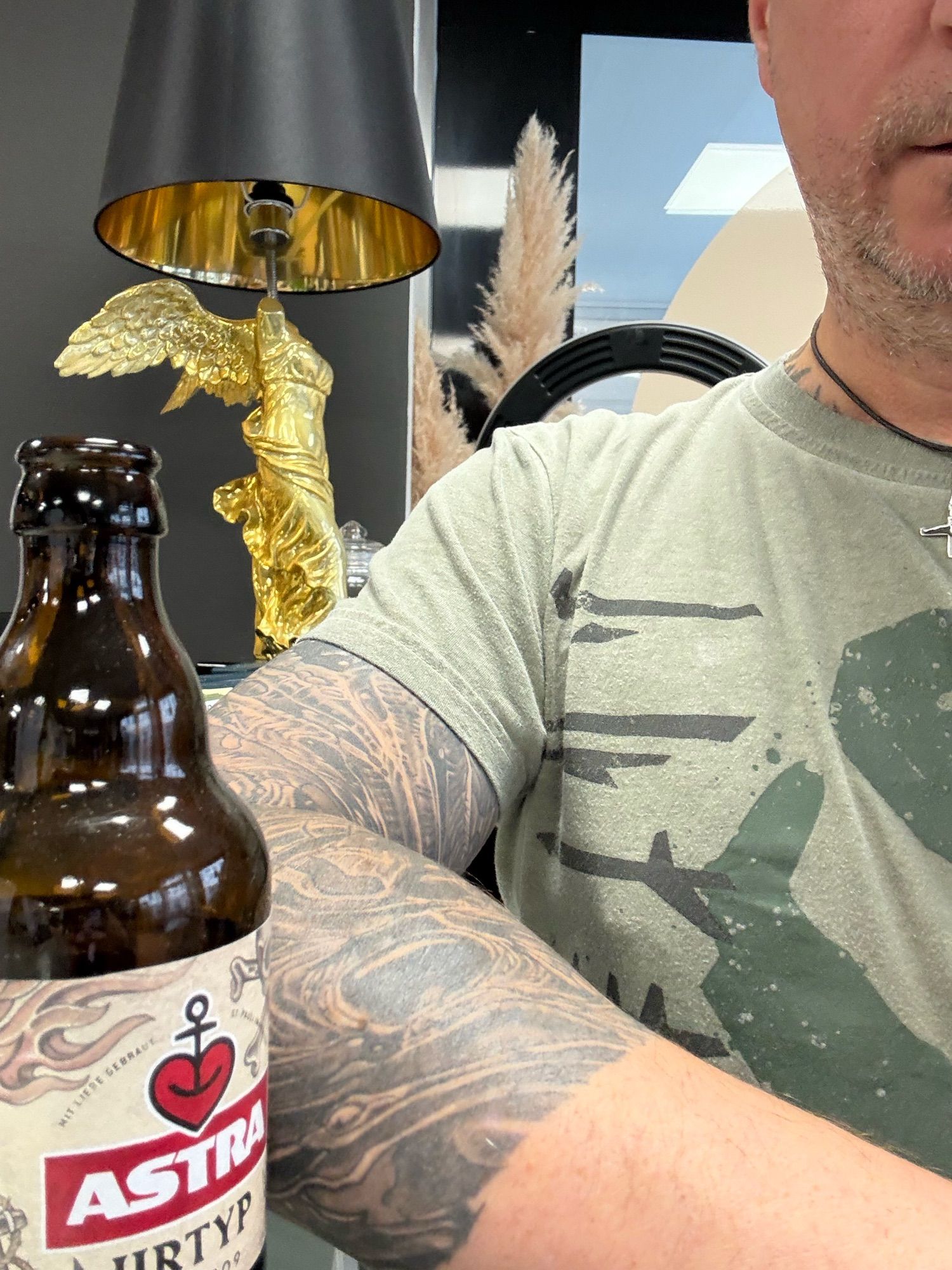 Ich stehe beim Friseur am Tresen im Eingangsbereich. Neben mir steht eine Flasche Astra-Pils.