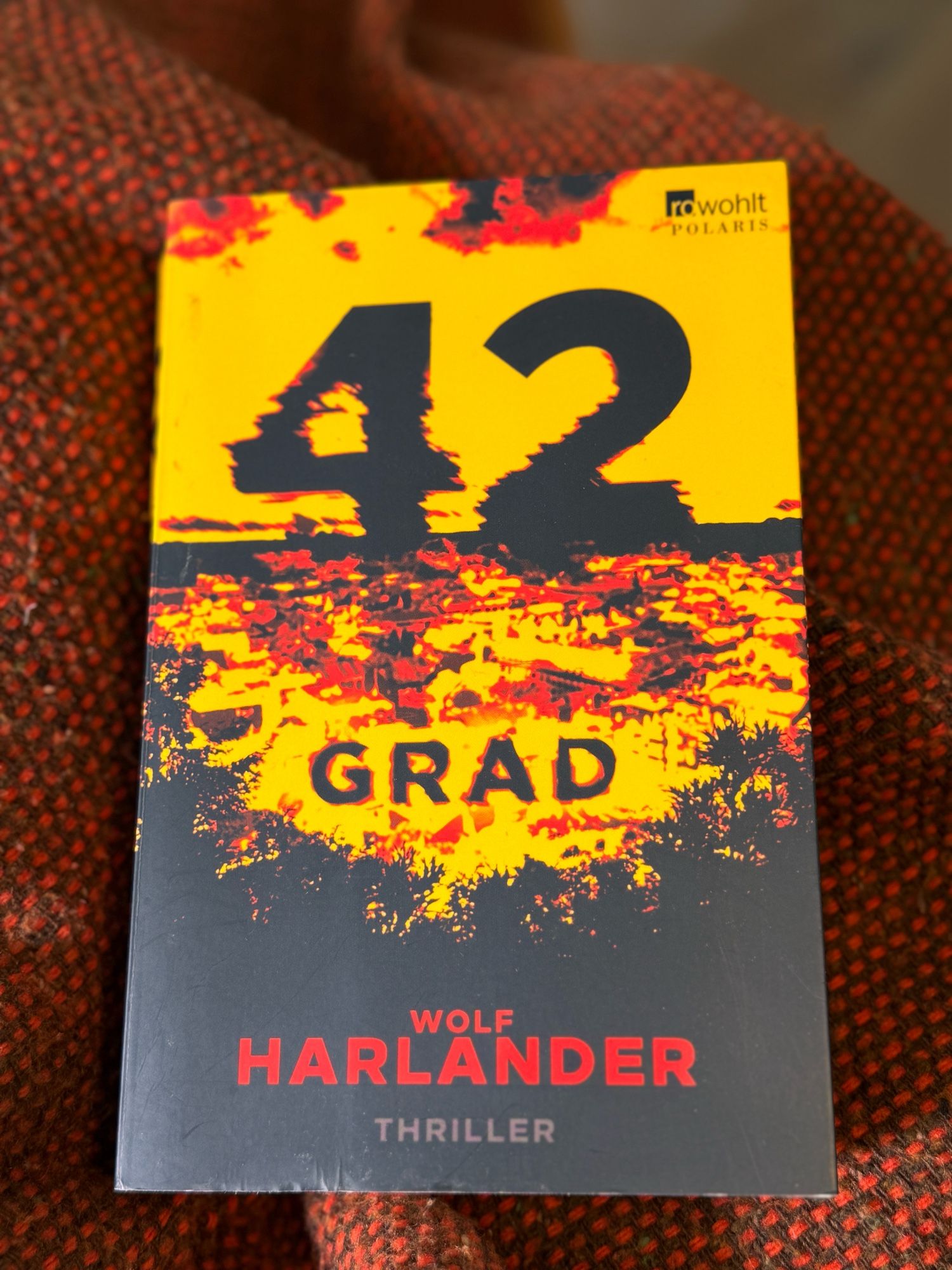 Ein Buch liegt auf einer Decke. Es ist „42 Grad“ von Wolf Harlander, erschienen bei Rowohlt Polaris.