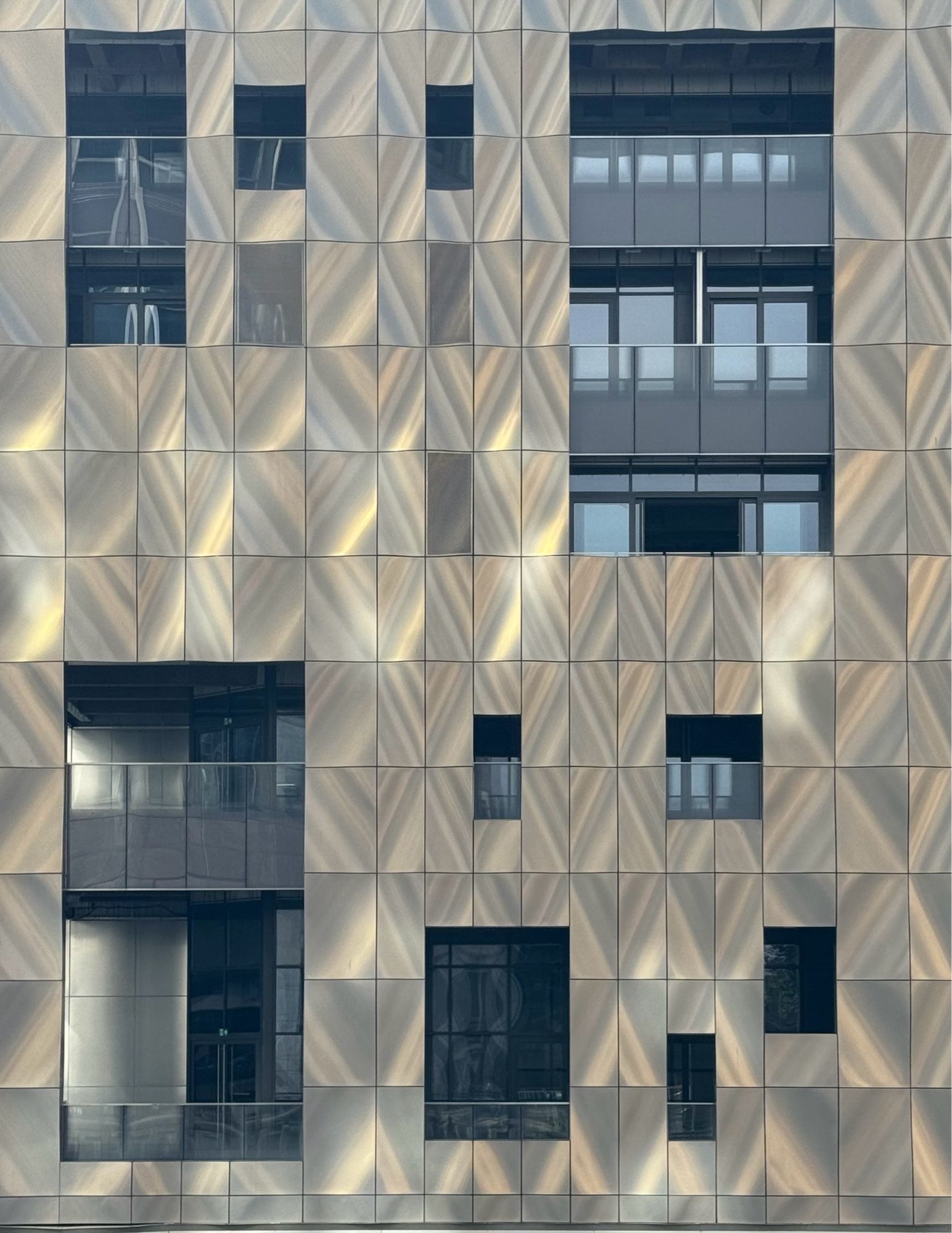 New building in Canary Wharf with golden diagonal wall patterns and higgledy-piggledy windows and balconies.