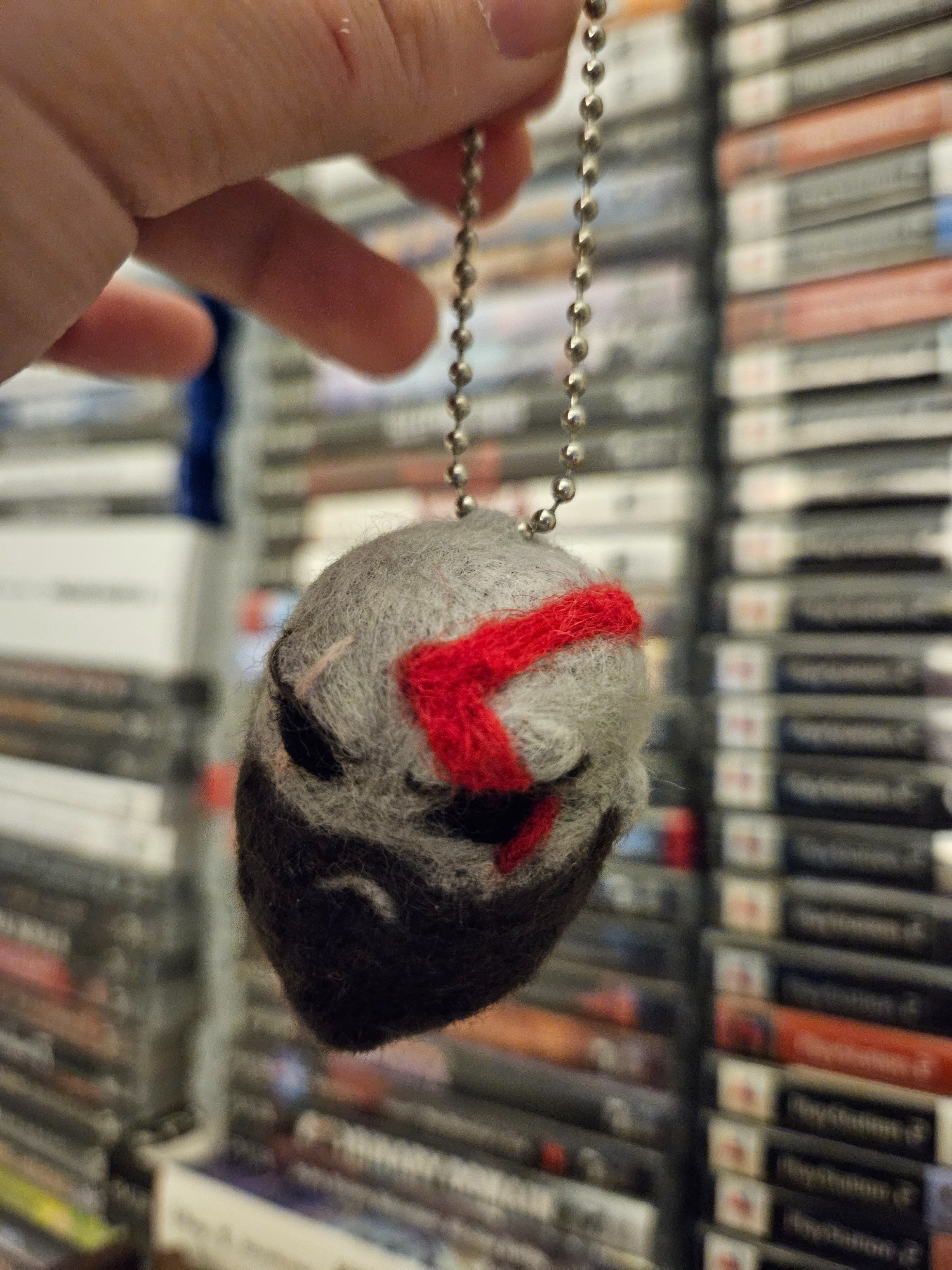 A needle felted keychain of Kratos from God of War's head