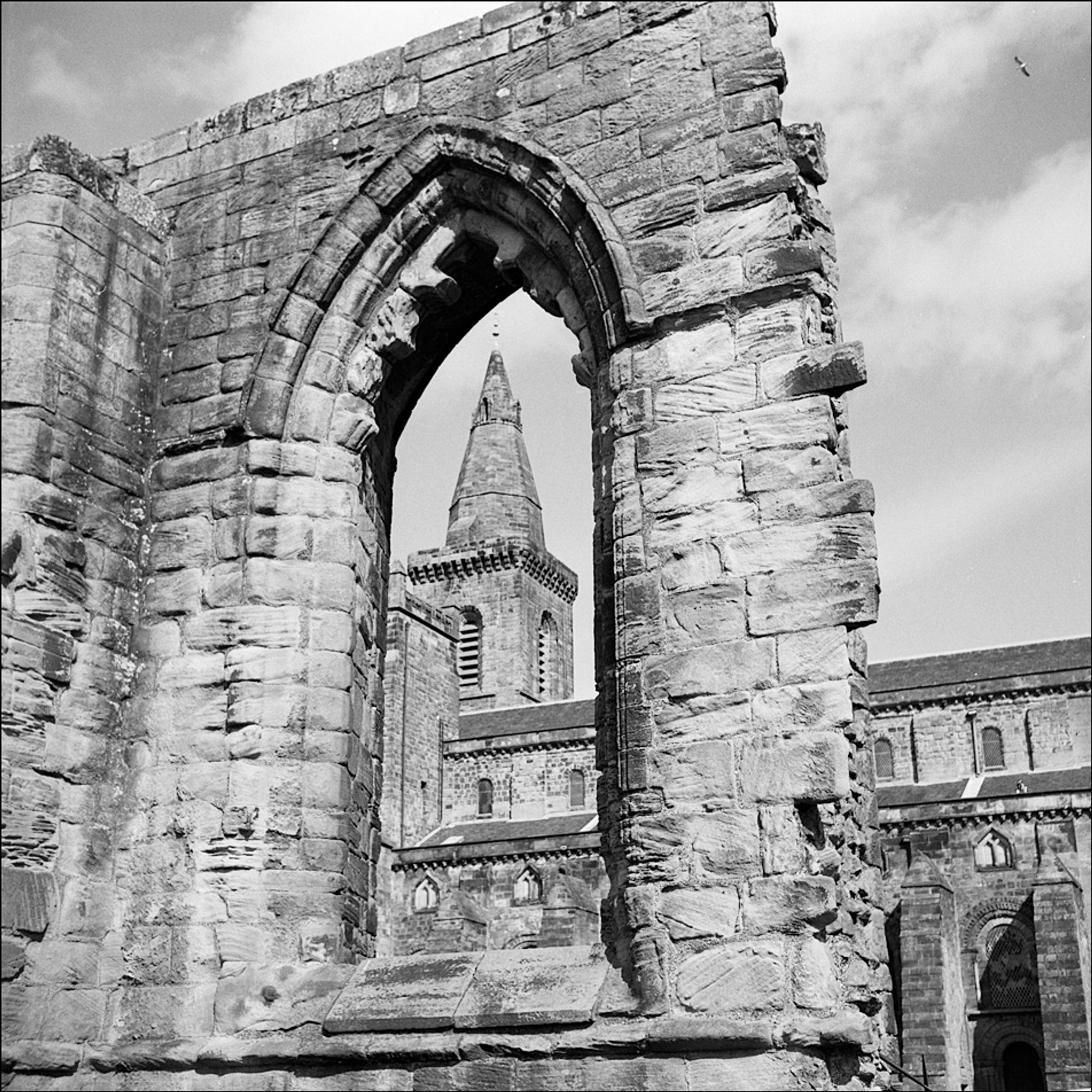 A church tower and spire seen through the empty arched window of a gothic ruin in Stirling, Scotland, in 2015.