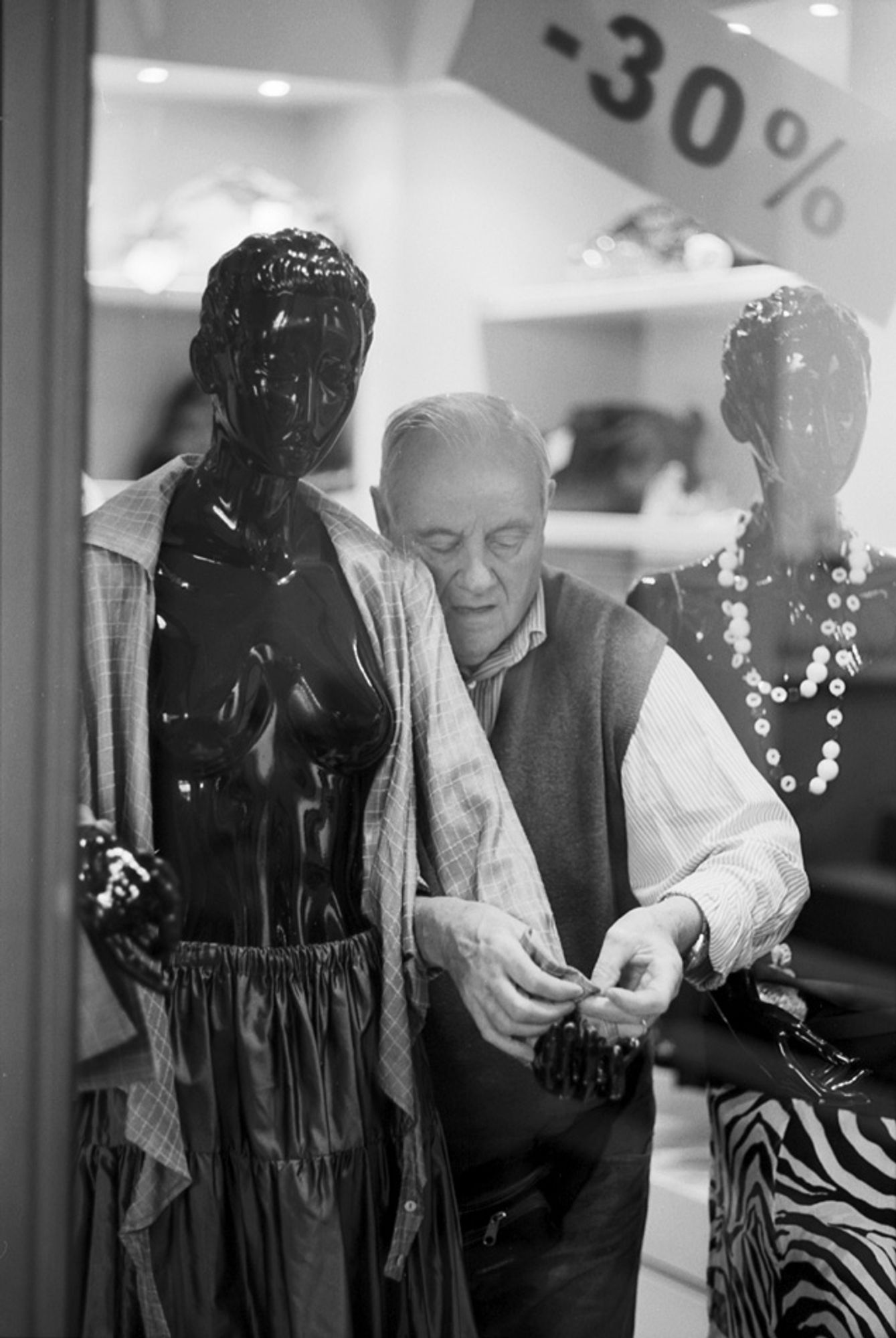 30% - a window dresser makes adjustments to a mannequin display in a clothing boutique, Bologna, Italy, 2011.