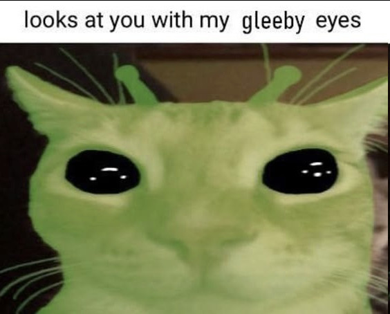 a picture of a cat that looks like an alien because of their green color, and the text on the top says "looks at you with my gleeby eyes"