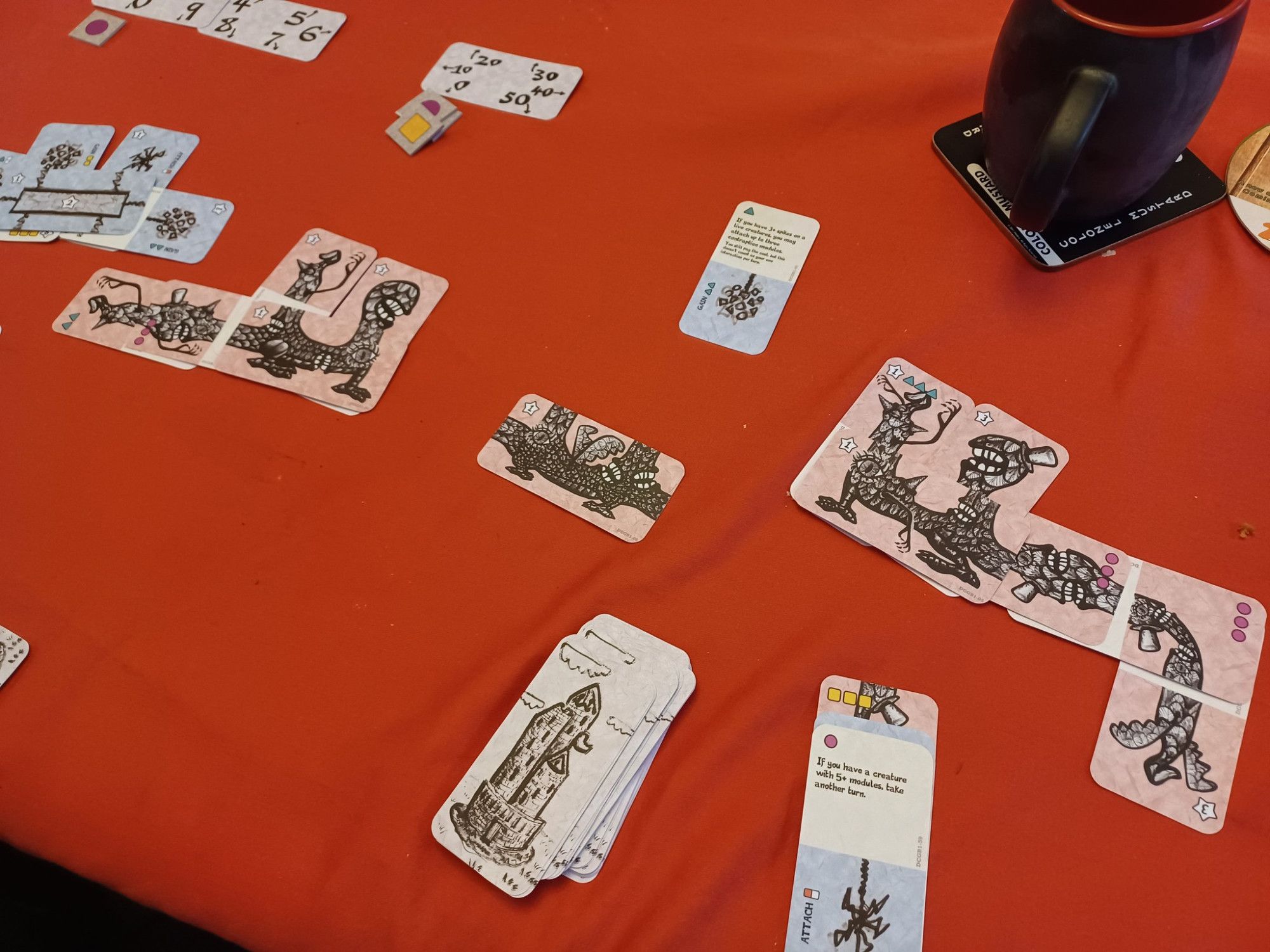 Various cards spread out on a table. Some are combined to create creatures or contraptions.