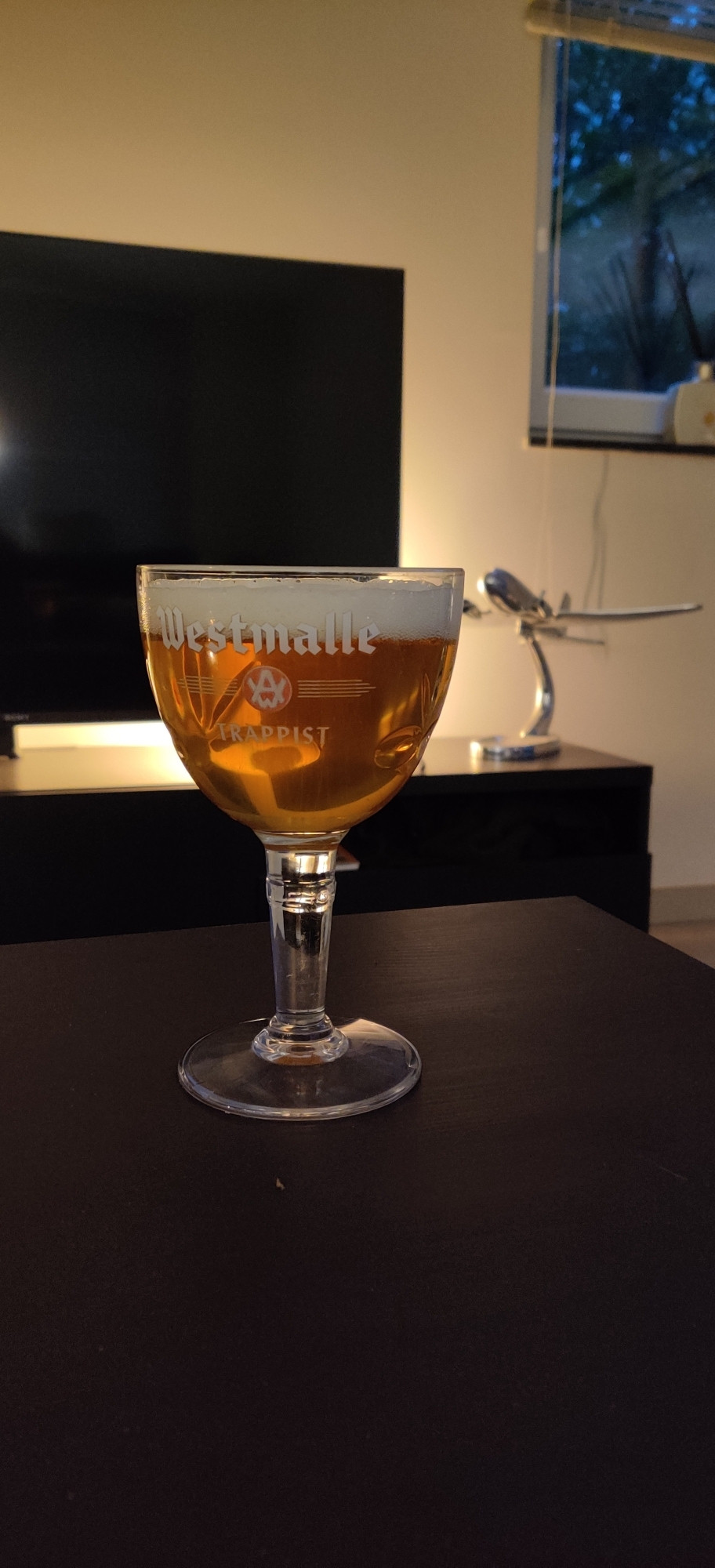 Un verre de bière trappiste devant une sculpture miniature de DC-3