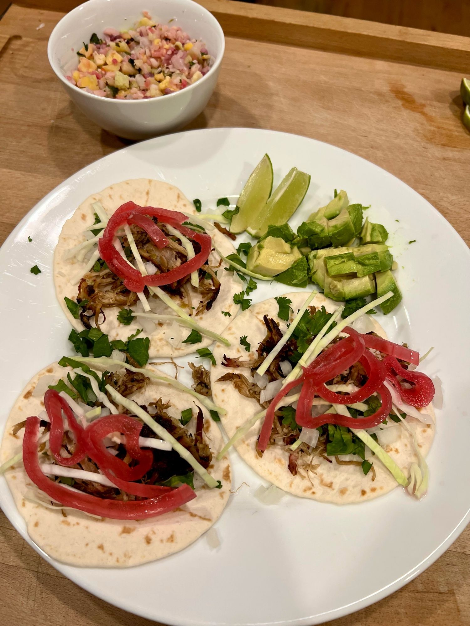 Carnitas tacos and cilantro lime riced cauliflower. The tacos are topped with cabbage and pickled red onions. Lime wedges and avocado on the side.