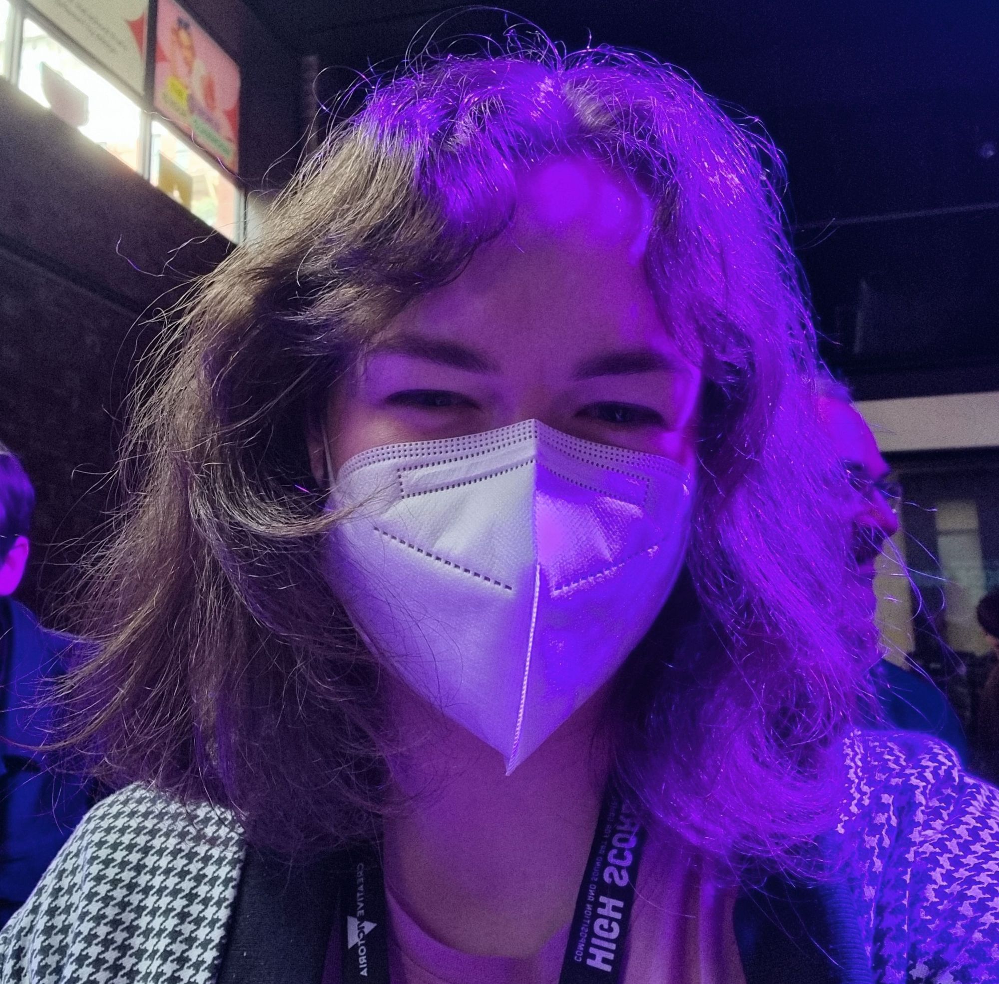 It's me! A white woman with messy brown hair and a face mask smiles at the camera.