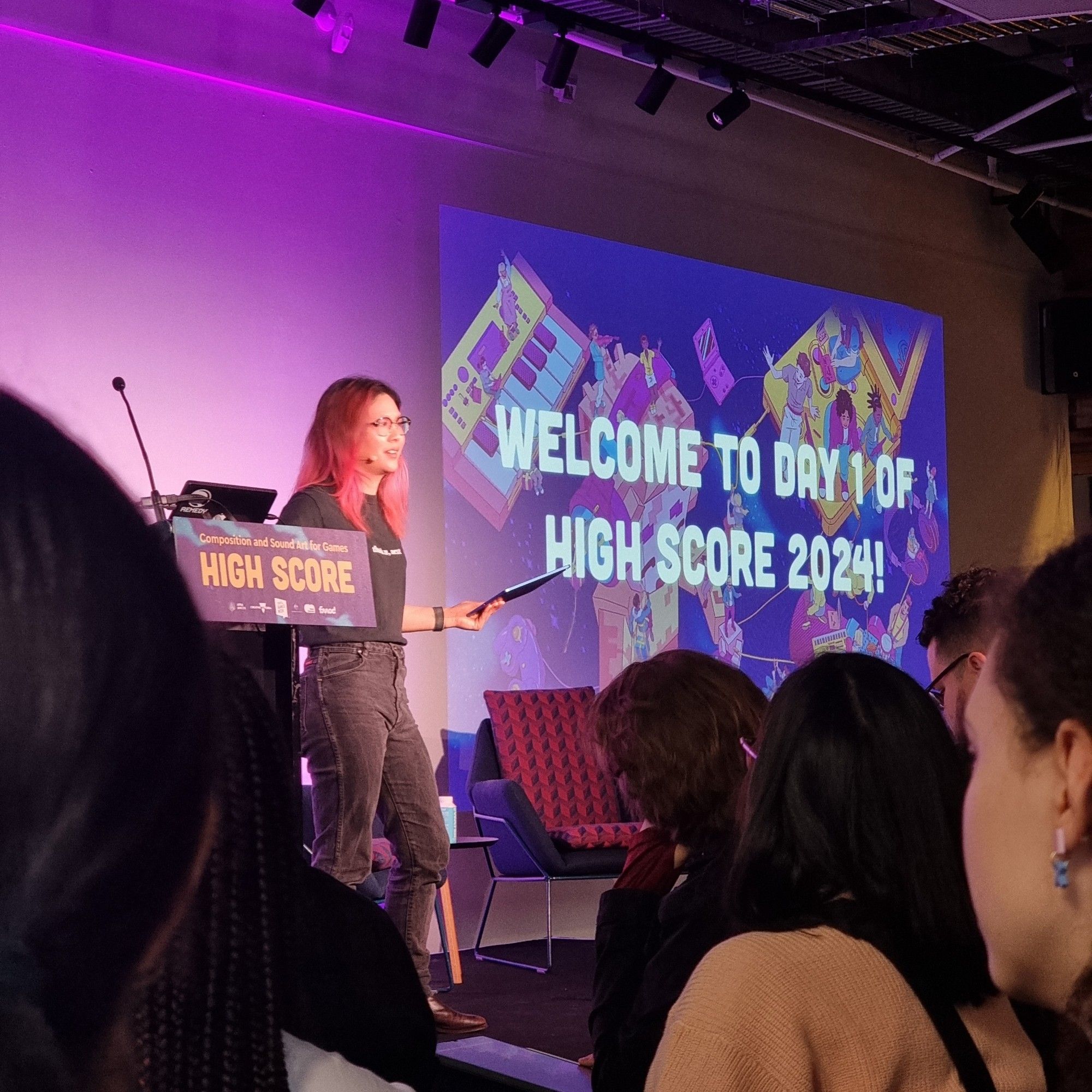 Rad Yeo lays down the law. She's introducing the first day of High Score 2024. A projected slide behind her says "welcome to day 1 of High Score 2024."