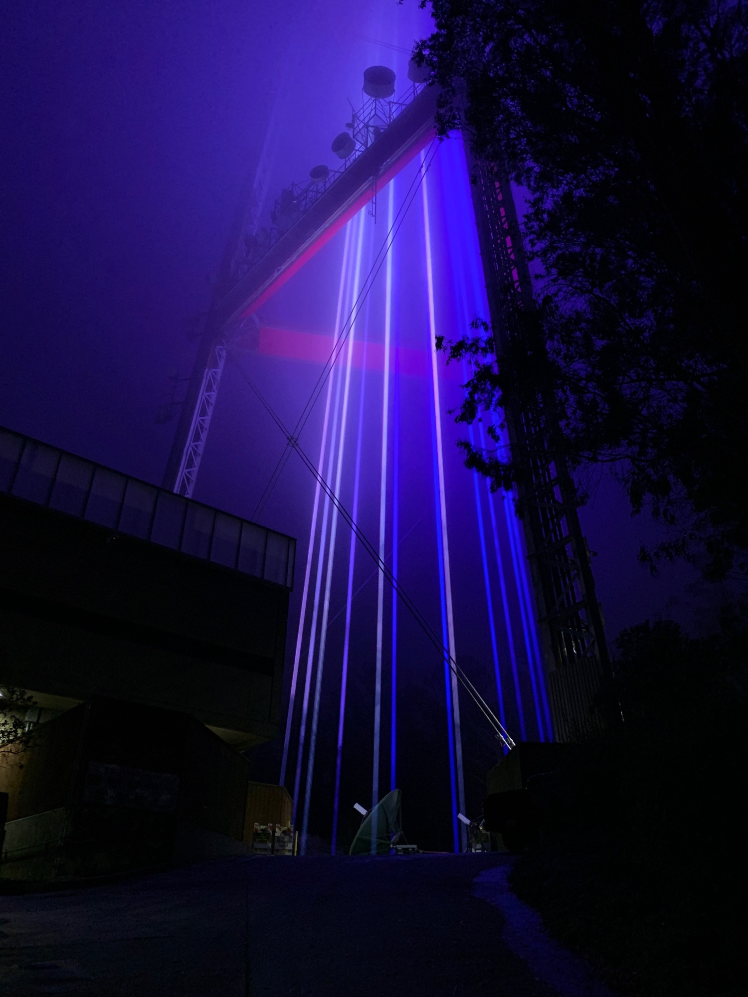 Blue lasers shining through middle of Sutro tower at its base 