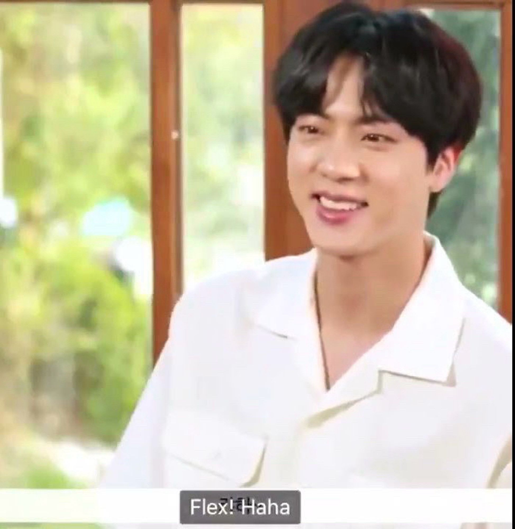 Screenshot of Jin of BTS. He’s smiling and the caption says, “Flex! Haha”