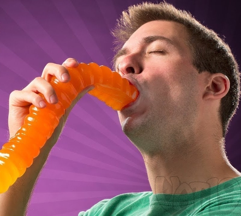 Cropped YT thumbnail of a Content creator sensually eating a giant gummy worm