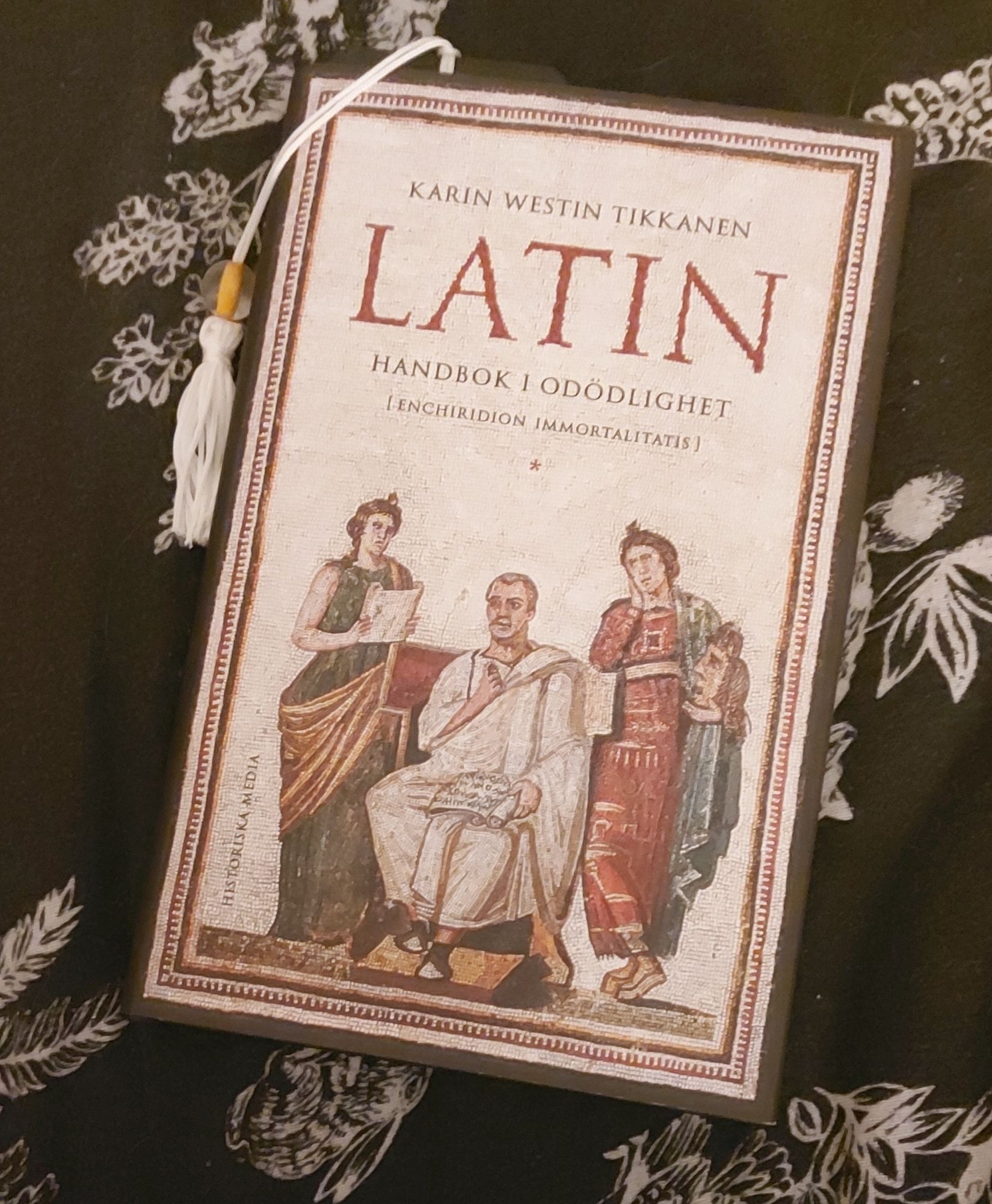 boken Latin : Handbok i odödlighet av Karin Westin Tikkanen. omslaget föreställer en mosaik av Vergilius och två av musorna.