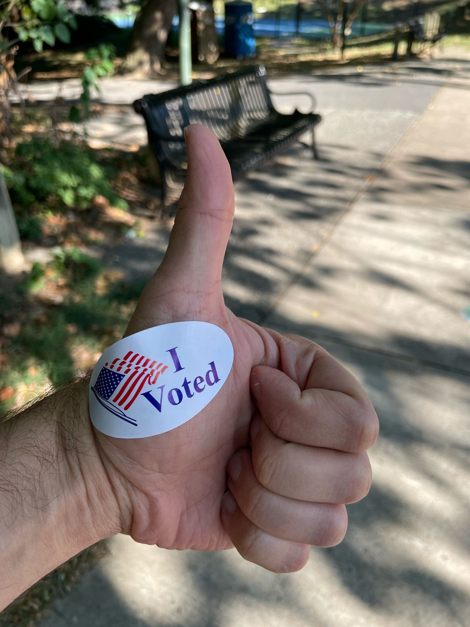 Close up picture of a hand giving a thumbs up with an “I Voted” sticker stuck on the hand.