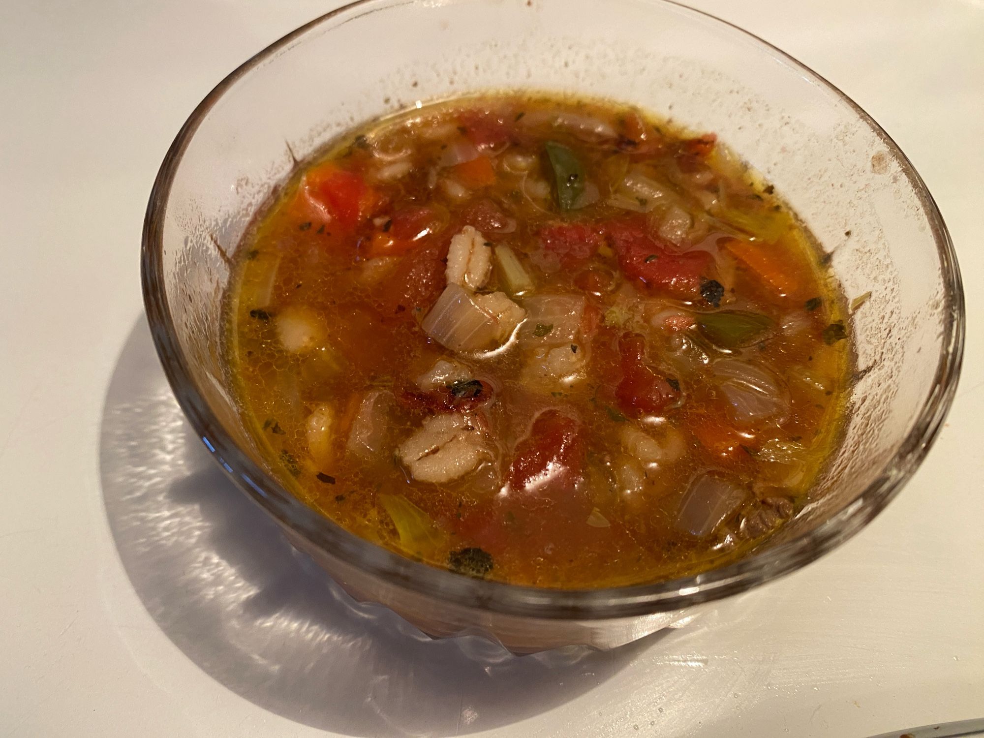 A glass bowl with beef vegetable barley  soup