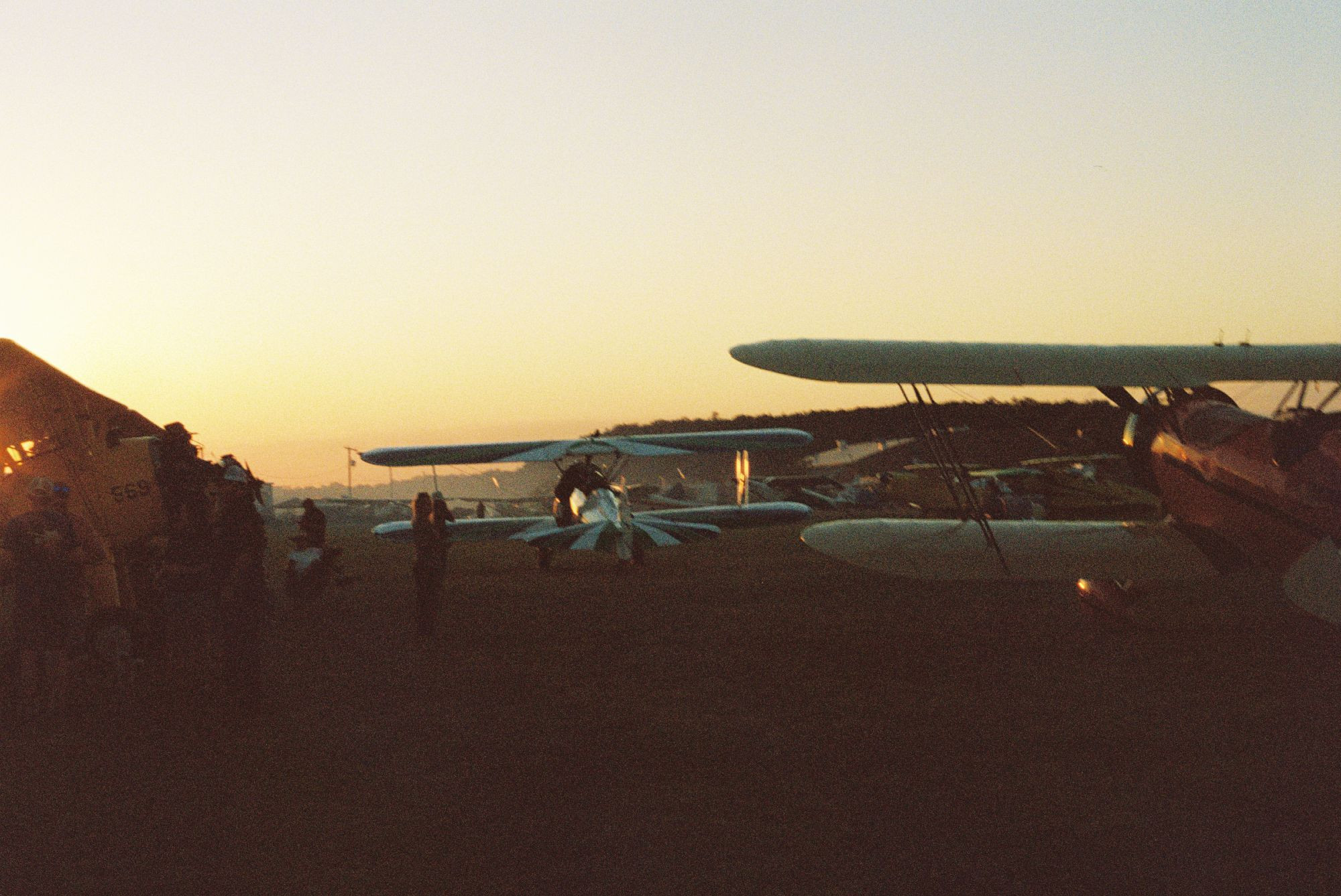 A film photo of a field of planes at sunset - it has a very nostalgic vibe.