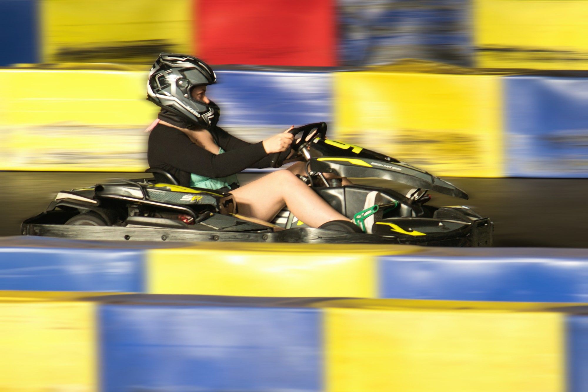 Jeune femme dans un karting. Ce dernier est relativement net sur une piste floue.