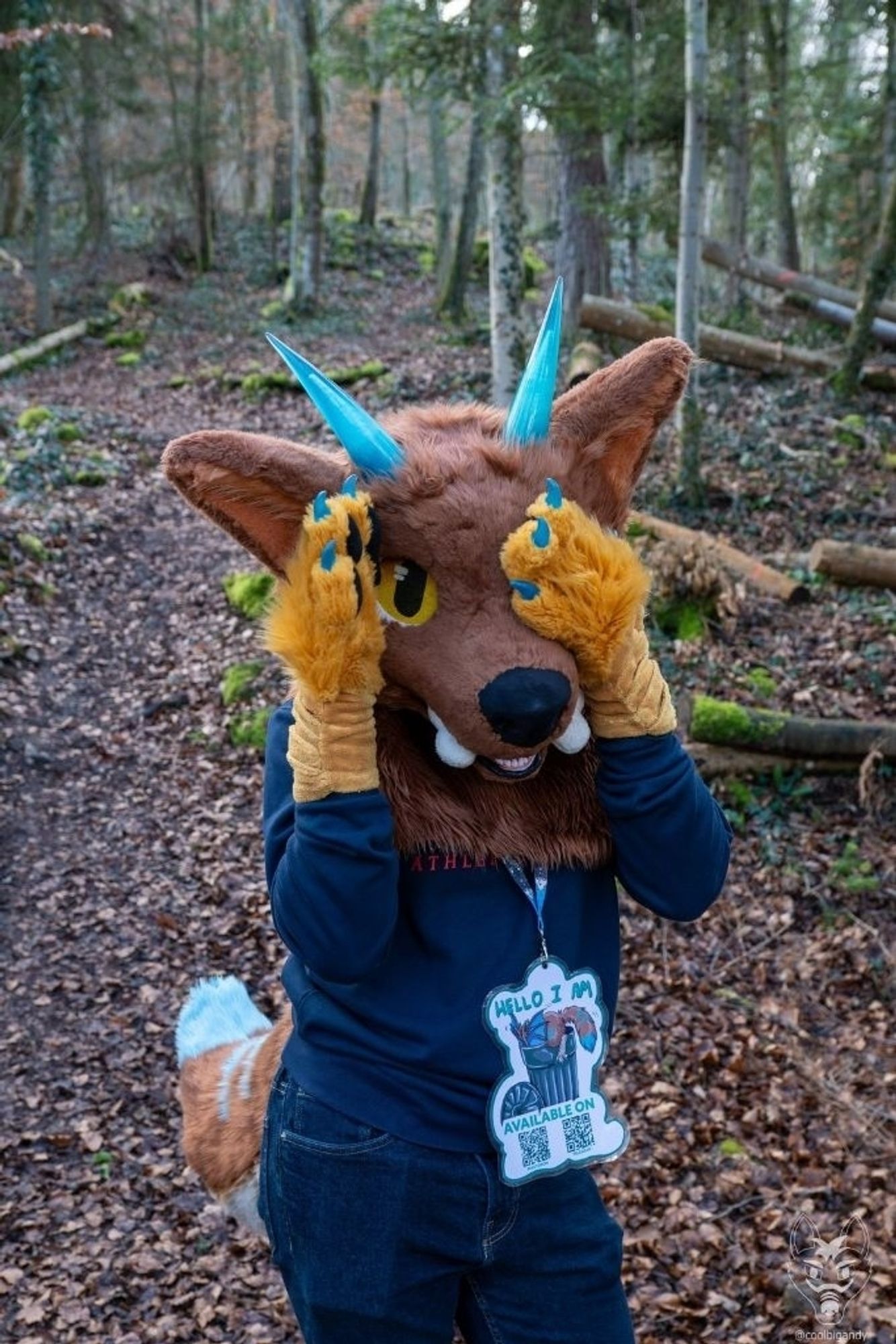 A picture of me in partial fursuit. Hands are covering my ears while the left one is slightly tilted, allowing the right eye to peek at the viewer