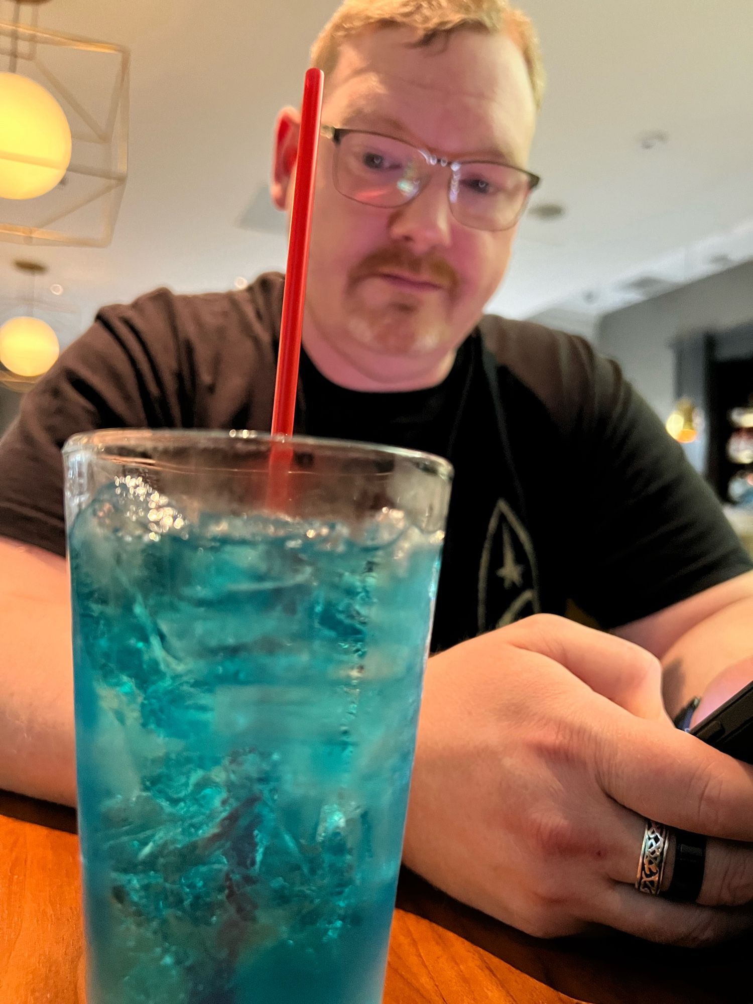 A man looks a blue coloured drink, “Romulan Ale”