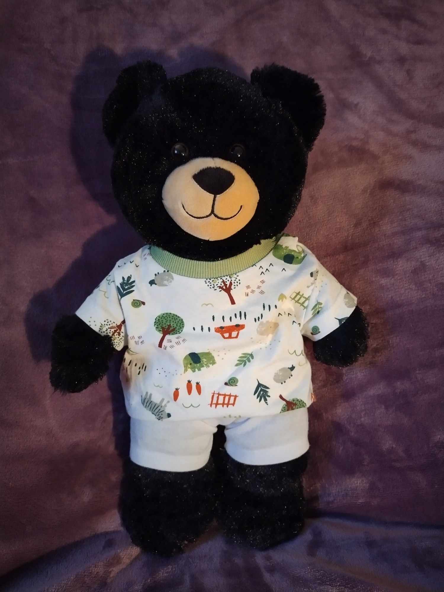 Brian a teddy bear wearing his pyjamas and ready for bed. His pyjamas have pictures of cars, trees, elephants, sheep, carrots, snails and a zebra on them.