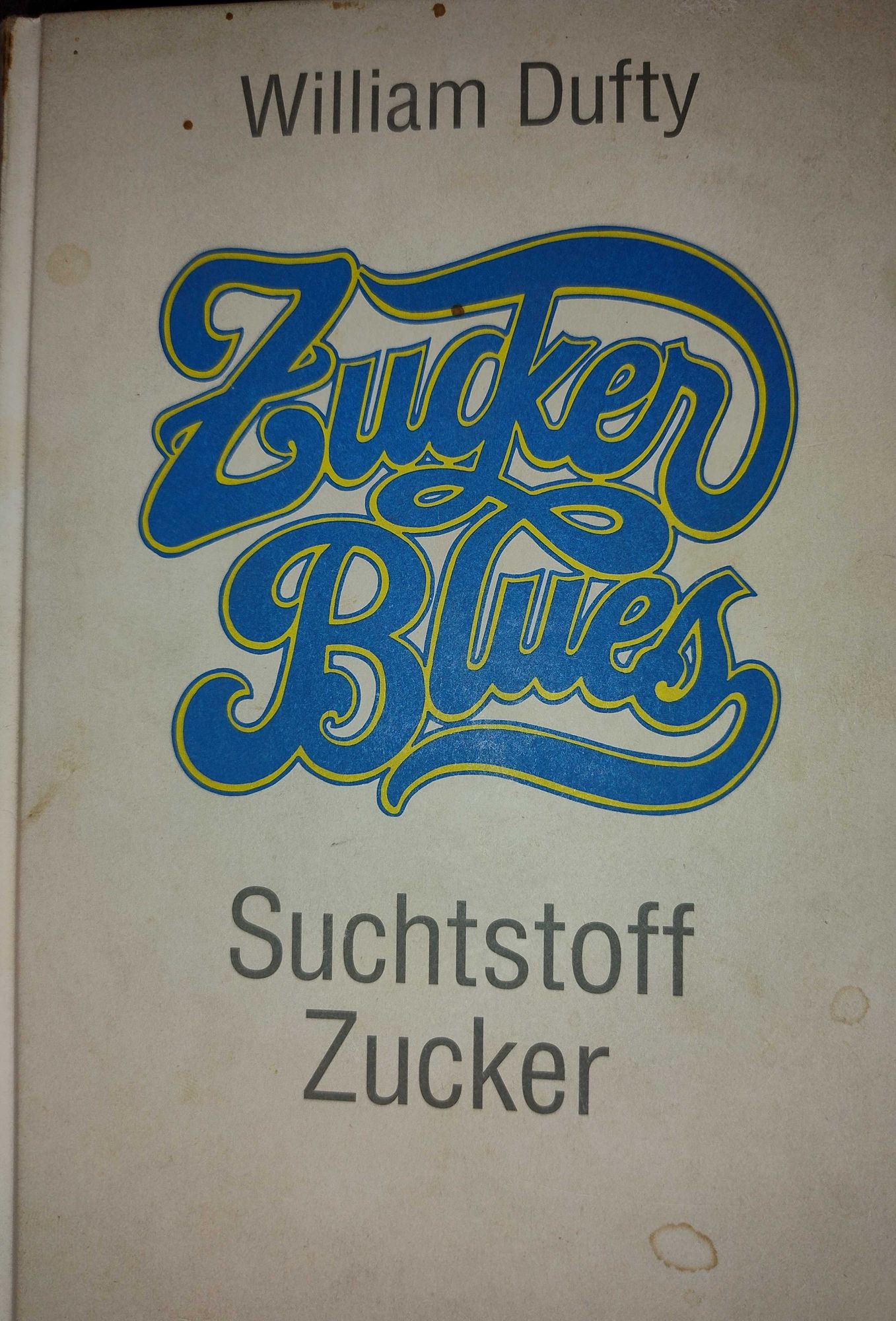 Buchcover Zuckerblues  Suchtstoff Zucker

In einer blau-gelben verschnörkelten 70er Jahre Schrift.