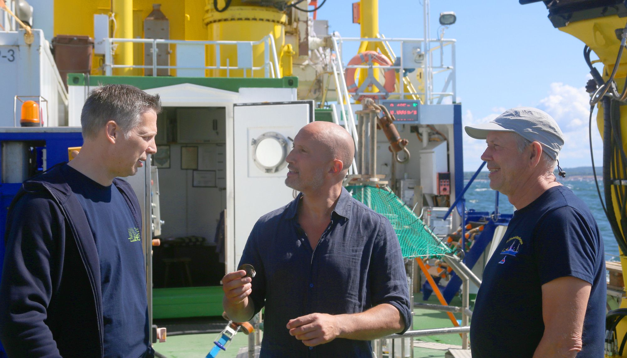 Benno Fürmann an Bord des IOW-Forschungsschiffes Elisabeth Mann Borgese im Gespräch mit IOW-Direktor Oliver Zielinski (l.) und IOW-Meeresbiologe Klaus Jürgens (r.). Foto: IOW / T. Bruhns