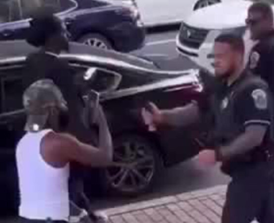 A cop getting ready to spray a Black man in the face with pepper spray.