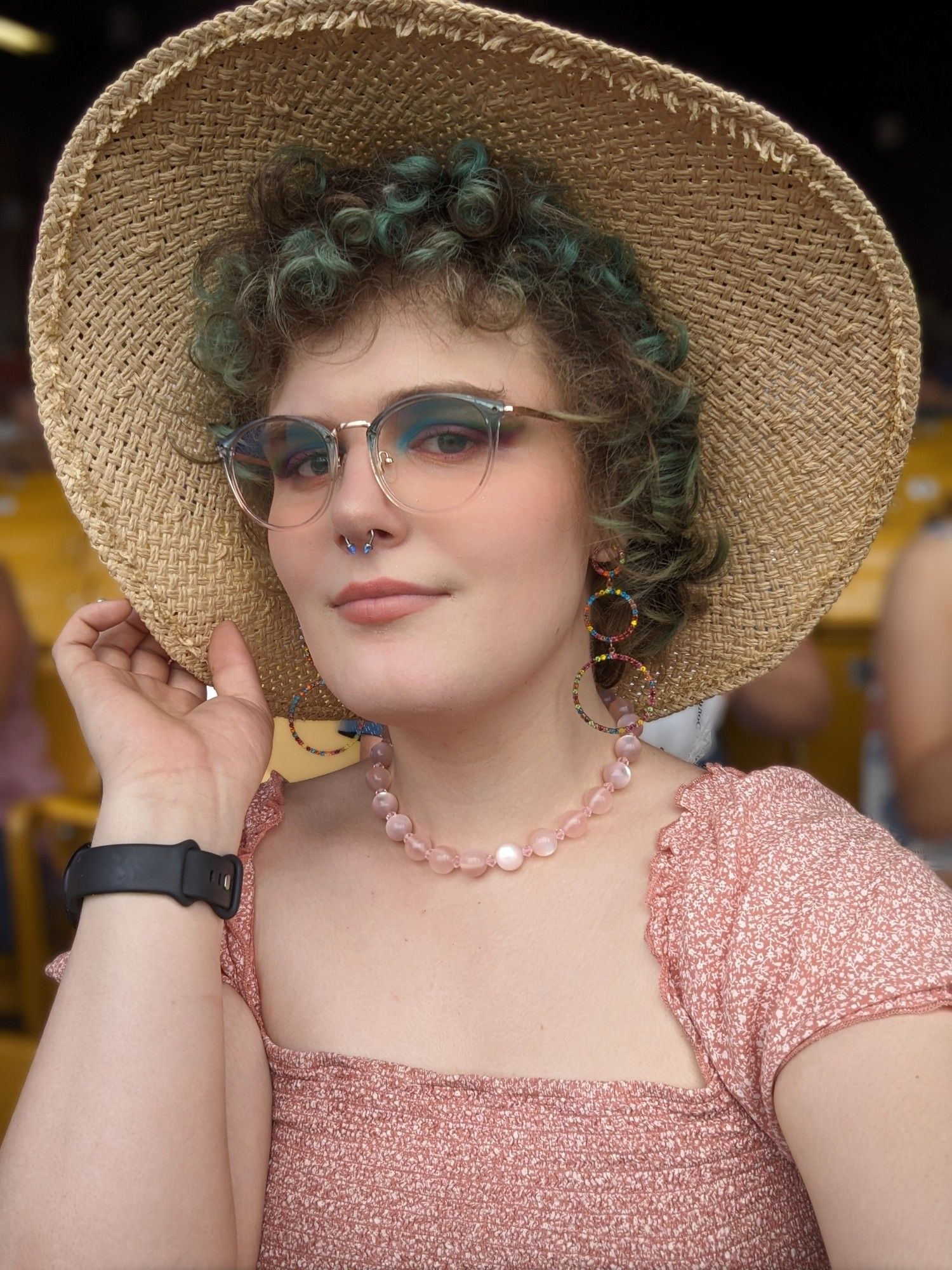 A selfie of Mana wearing her short pink sundress, her fake pink pearl necklace, and a weaved sunhat.
She has reddish-pink lipstick on, and her eyeshadow is a beautiful mix of baby blue, green, and pink and purples.