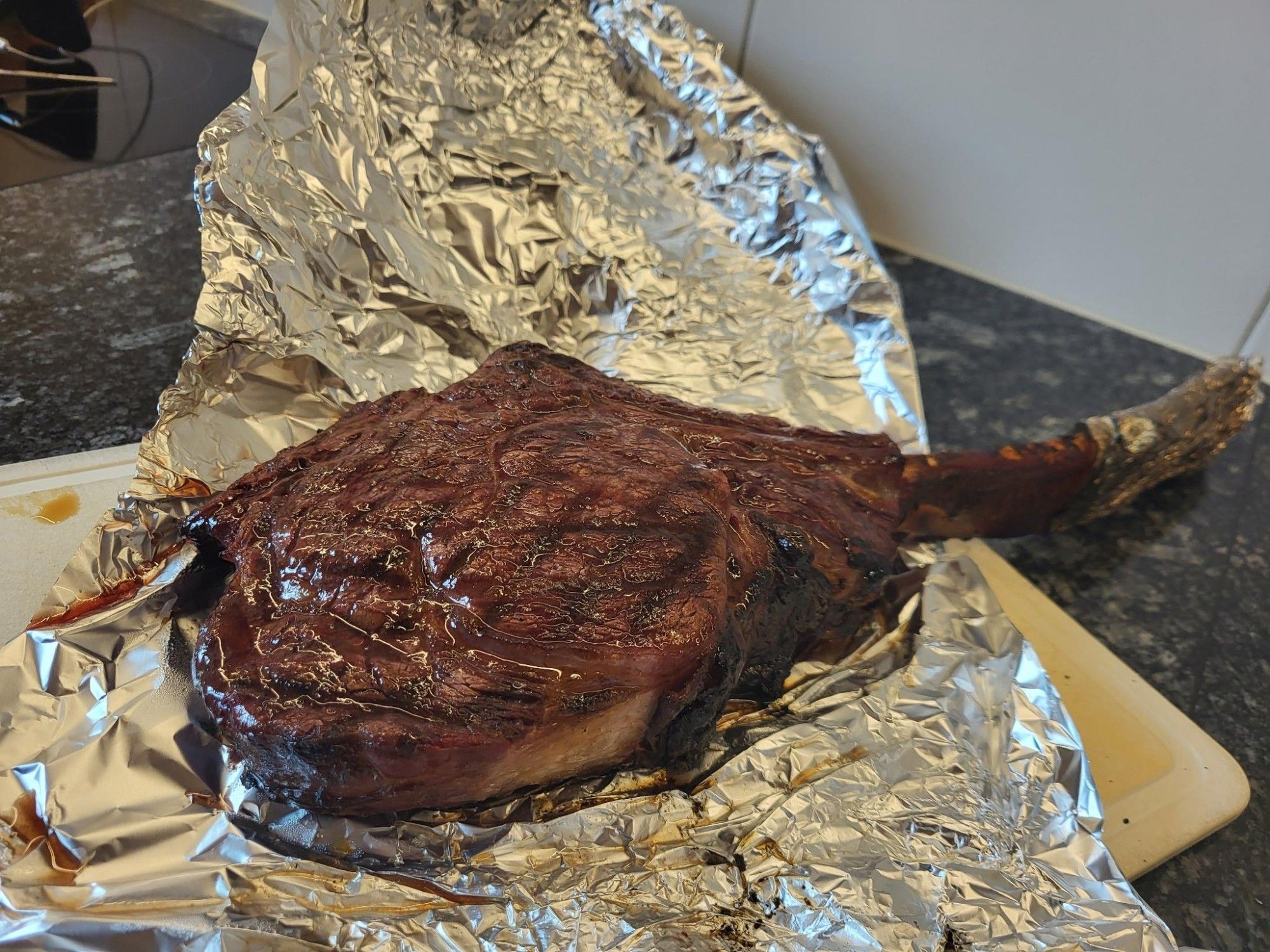 Ein fertig gegartes Tomahak-Steak liegt auf Alufolie.