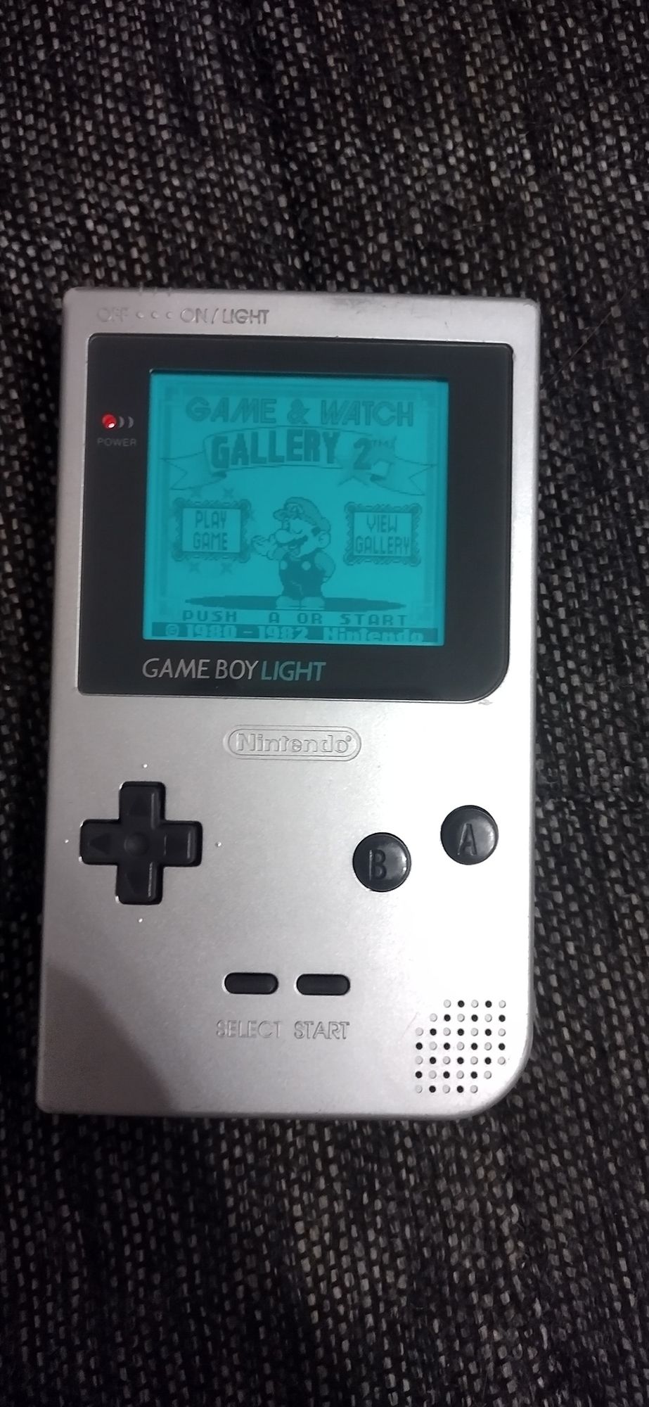 Game Boy Light, with the back-light on, showing the title screen for Game and Watch Gallery 2