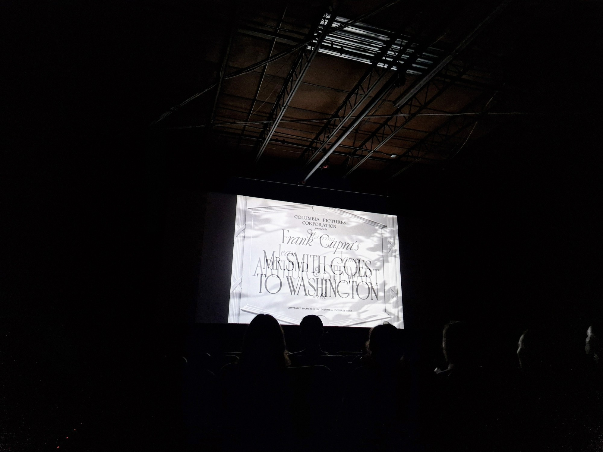 Dark cinema. Screen shows title screen for 'Mr Smith goes to Washington.'