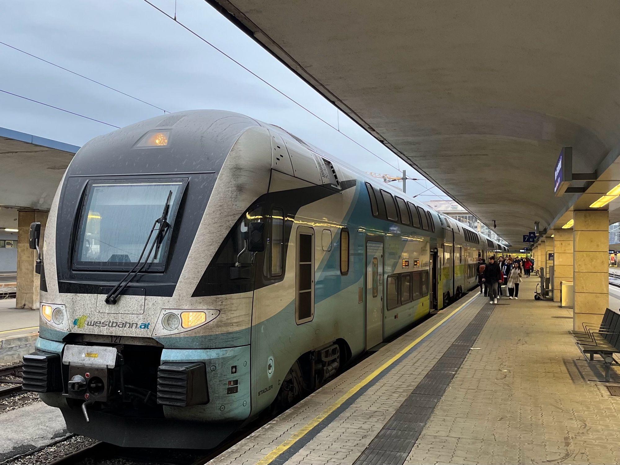 Zug der Westbahn am Westbahnhof, bedeckter Himmel, Personen am Bahnsteig