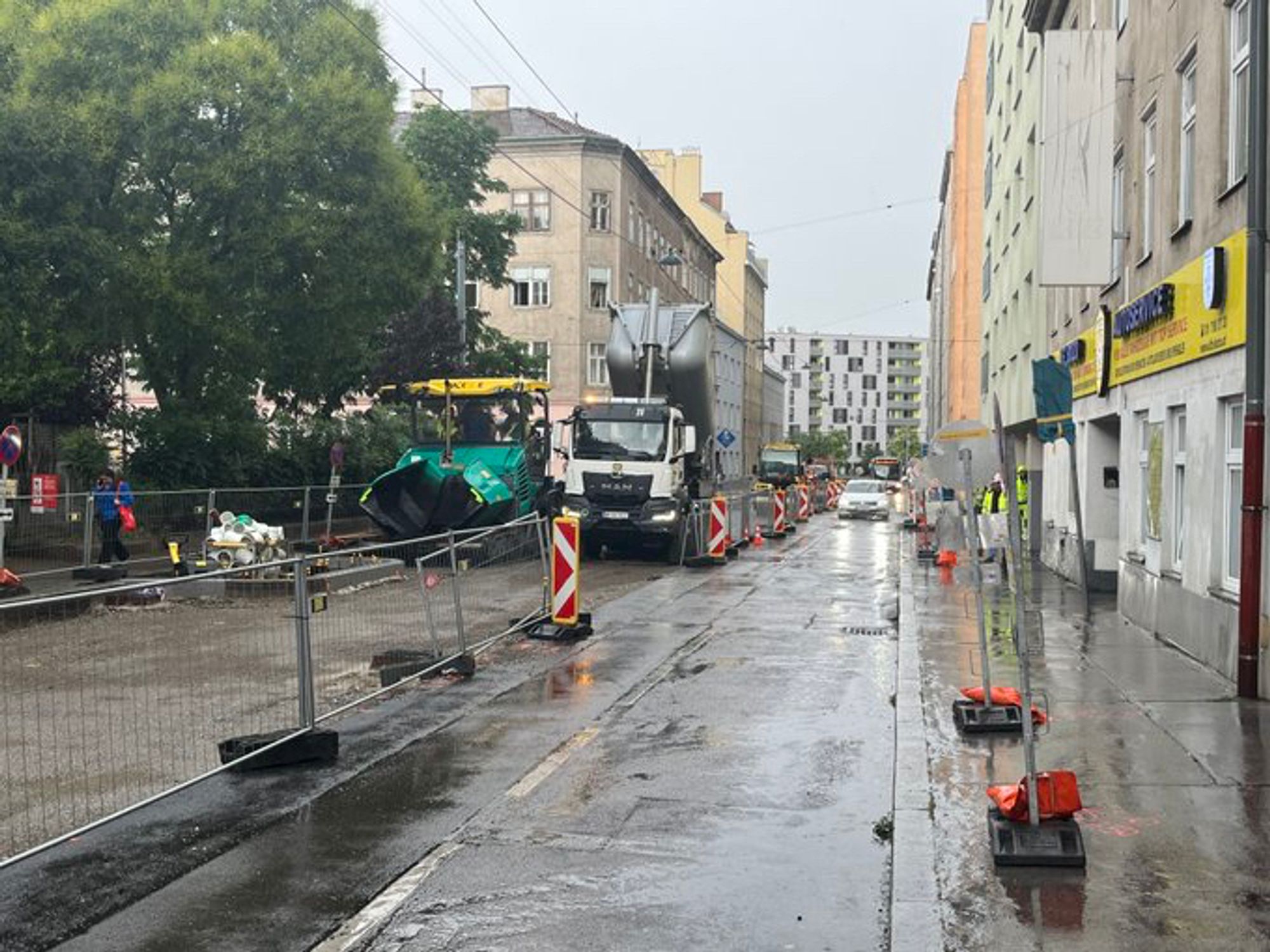 Baustelle in der Herndlgasse für den neuen Fahrrad-Highway in Wien Favoriten, eine von zwei Fahrspuren abgesperrt, Straßenfertiger und Lastwagen