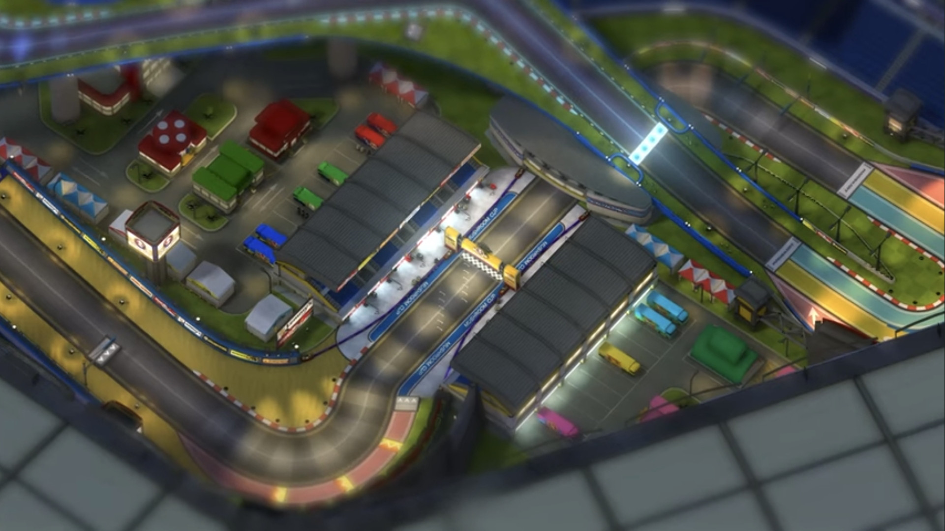 A camera mode capture of a Mario Kart 8 track from afar, showing many additional infrastructural and logistical elements to support the races on the track