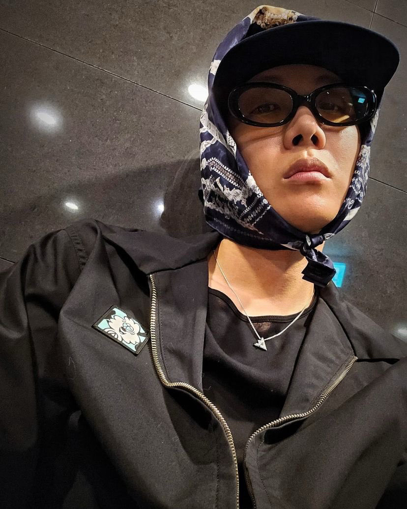 Jhope wearing black sunglasses and scarf over a cap.