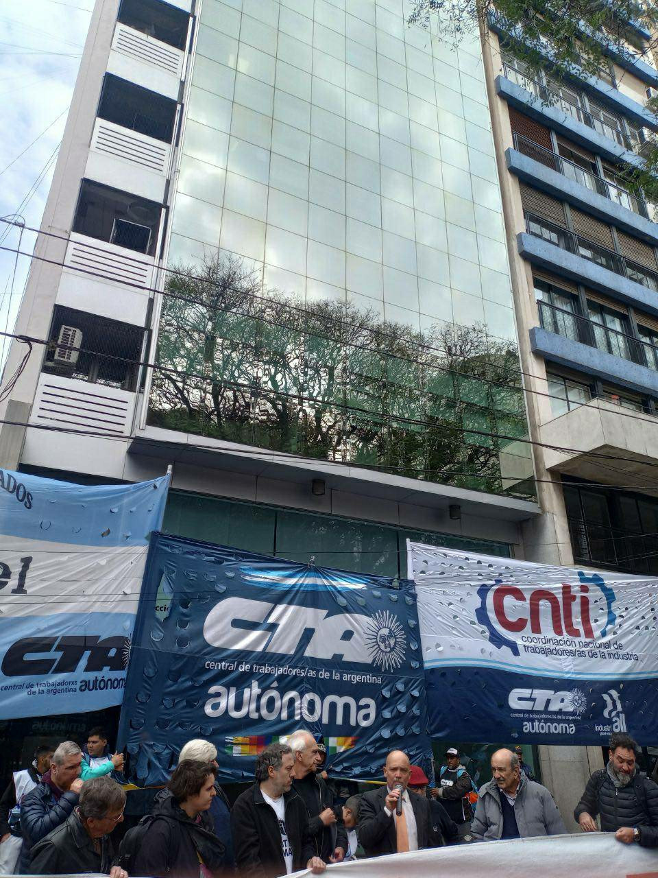 A groups of people in front of many union banner. Aan is giving a speech.