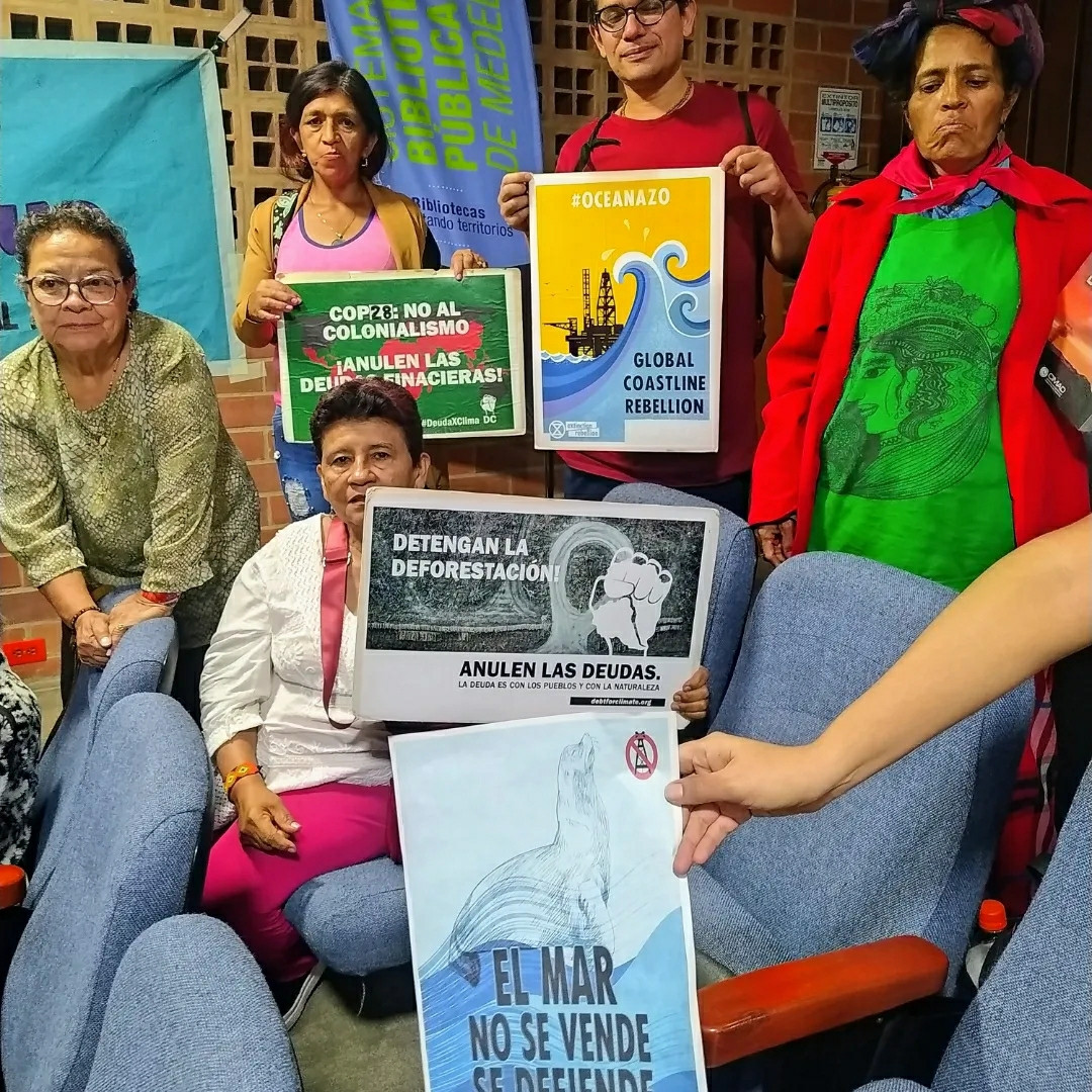 Women holding placards. Cop28: no colonialism. Cancel the debts.of the climate south. Stop deforestation.