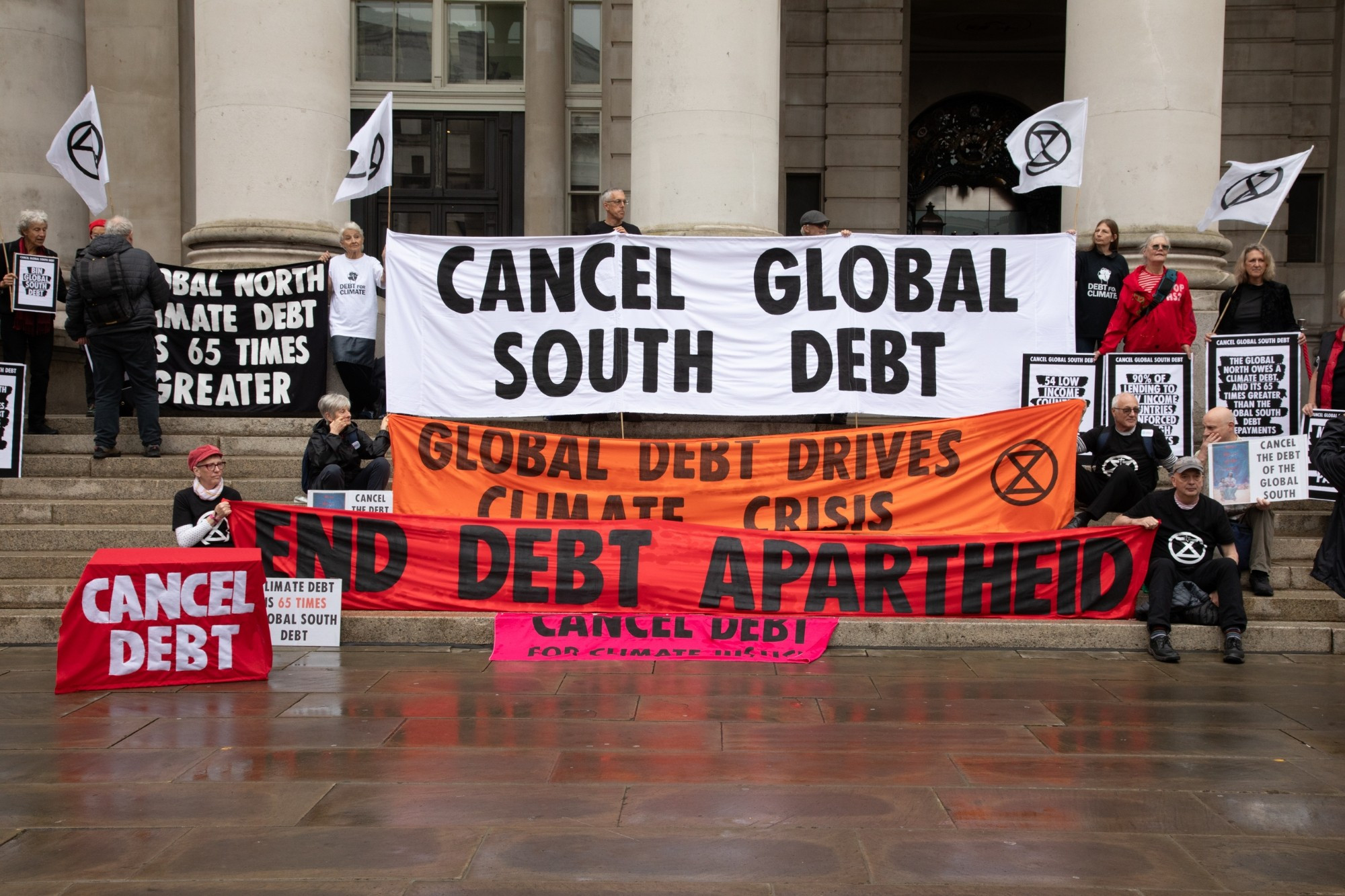 A group of people in front of the bank of England wir Banners and placards. 
Cancel global south debt. Global debt drives climate crisis. End debt apartheid.