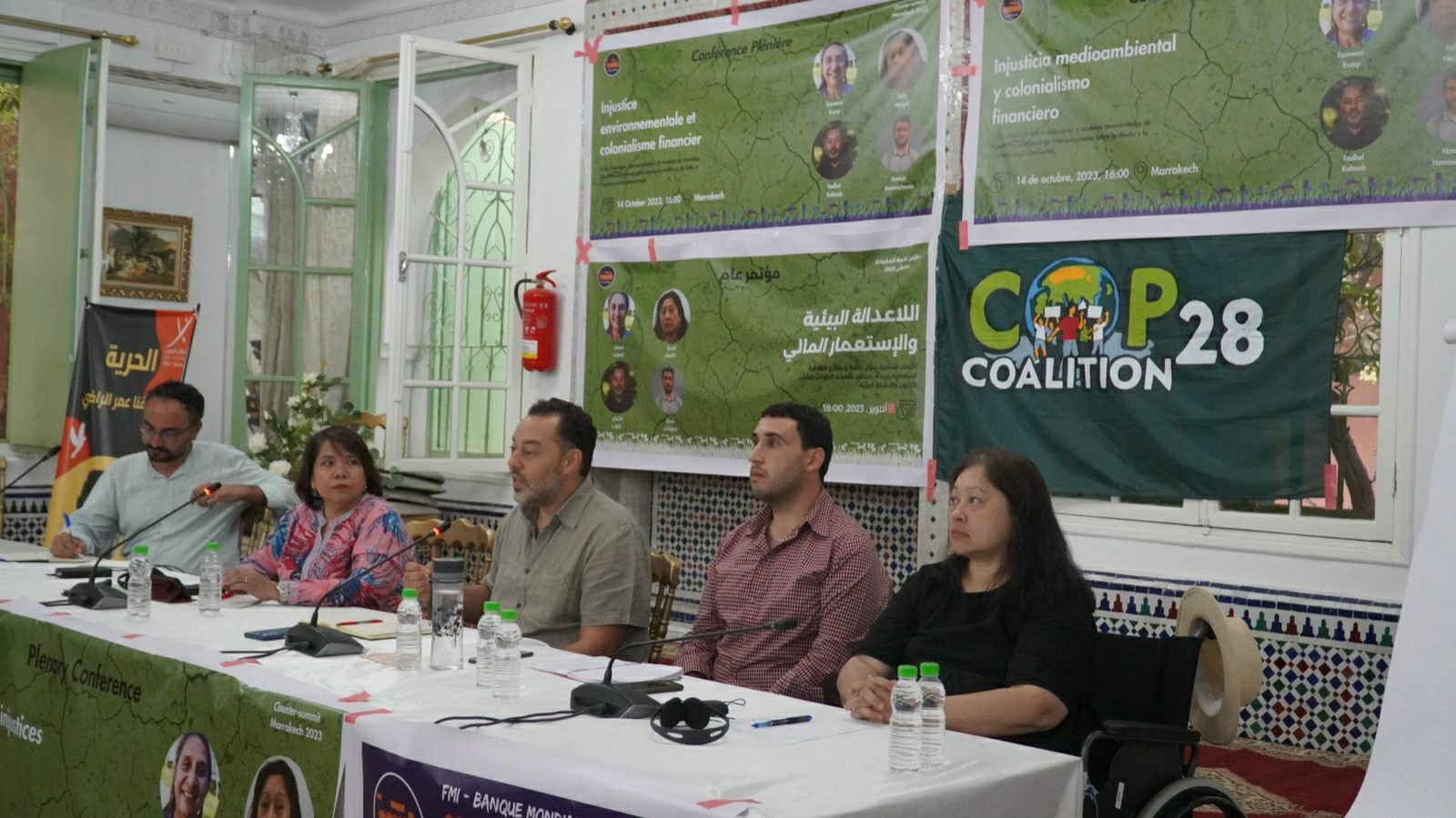 5 people sitting on a podium. Behind them are banners from the COP28Coalition