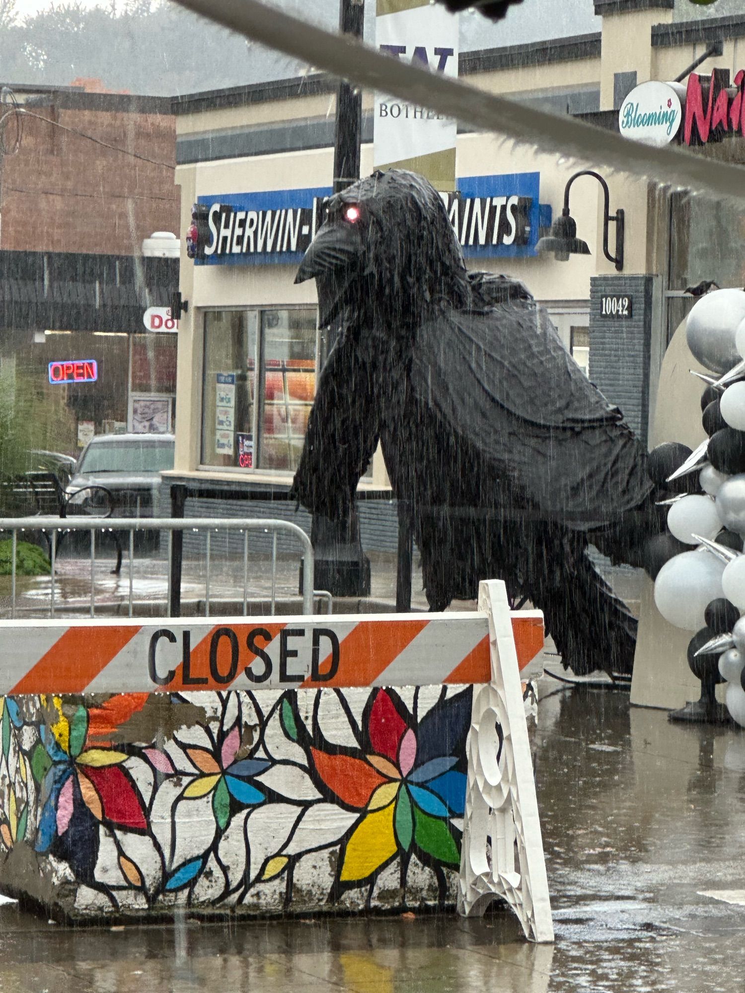 a human-sized audio-animatronic crow with glowing eyes, cawing in torrential rain