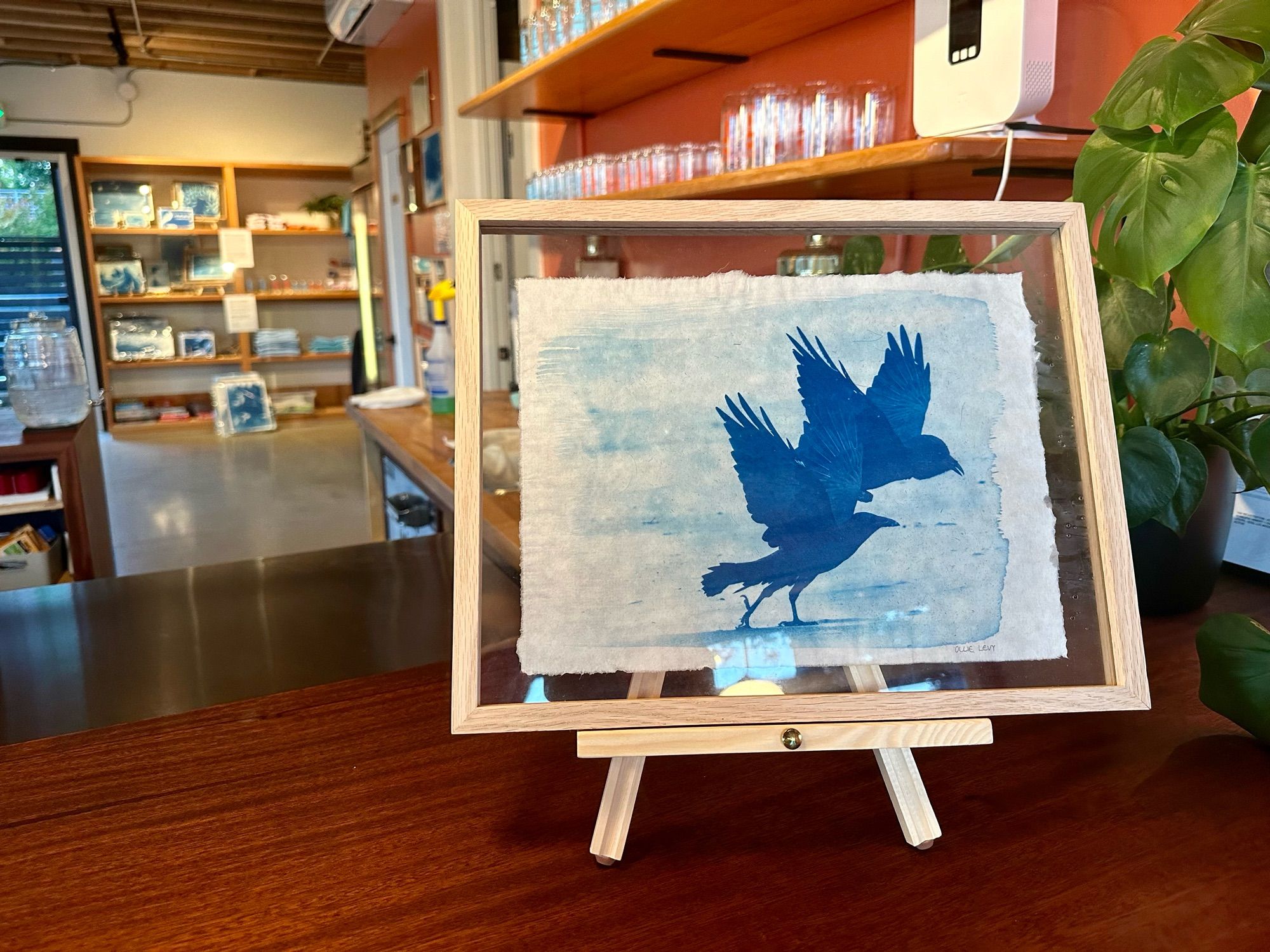 A blue-toned print of two ravens, on an easel in the same taproom.