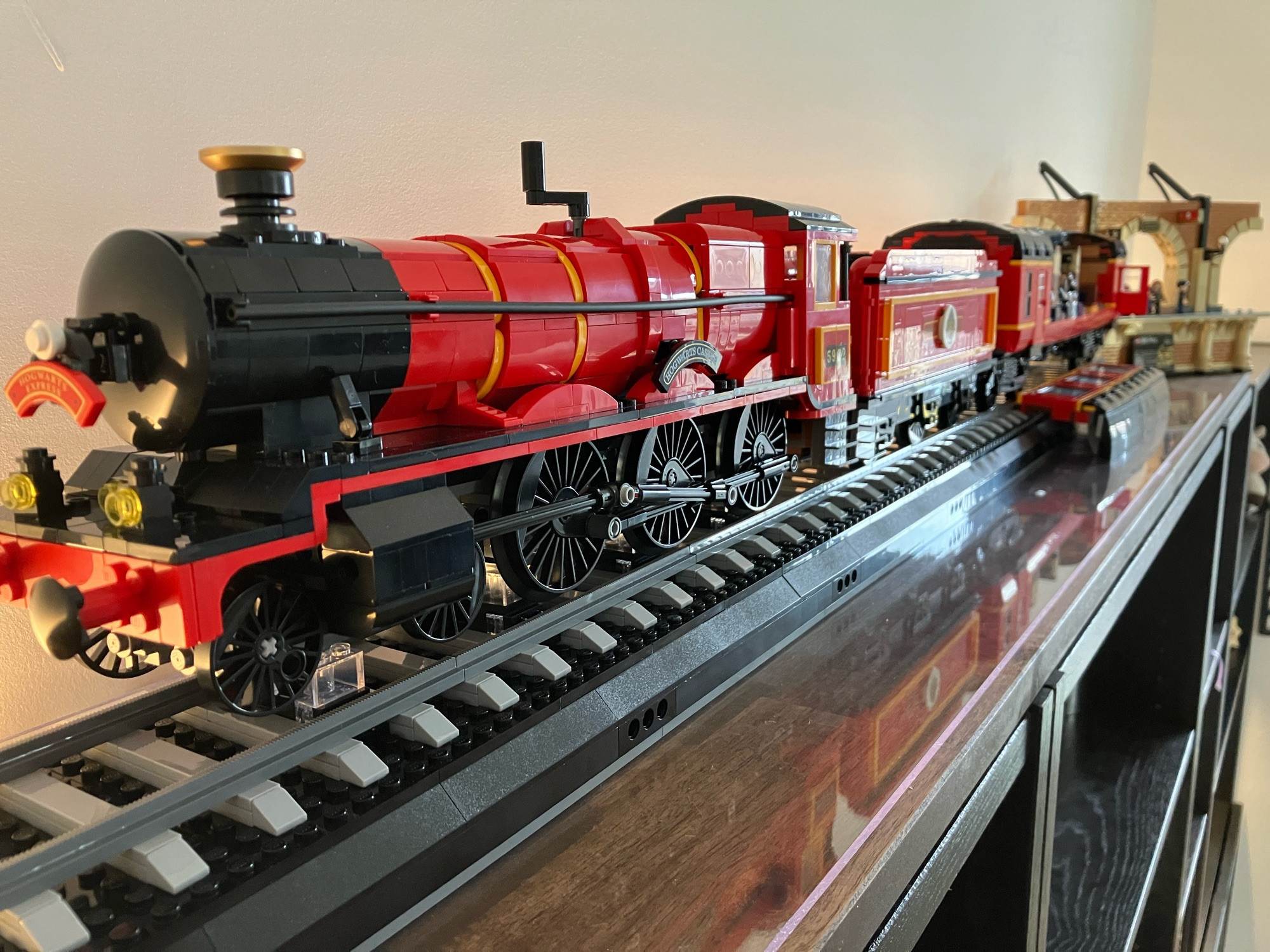 Der Hogwarts Express Zug von Lego von vorne fotografiert, man sieht der roten Zug, Kohletender und Personenwagen. Sehr im Hintergrund, der Bahnsteig