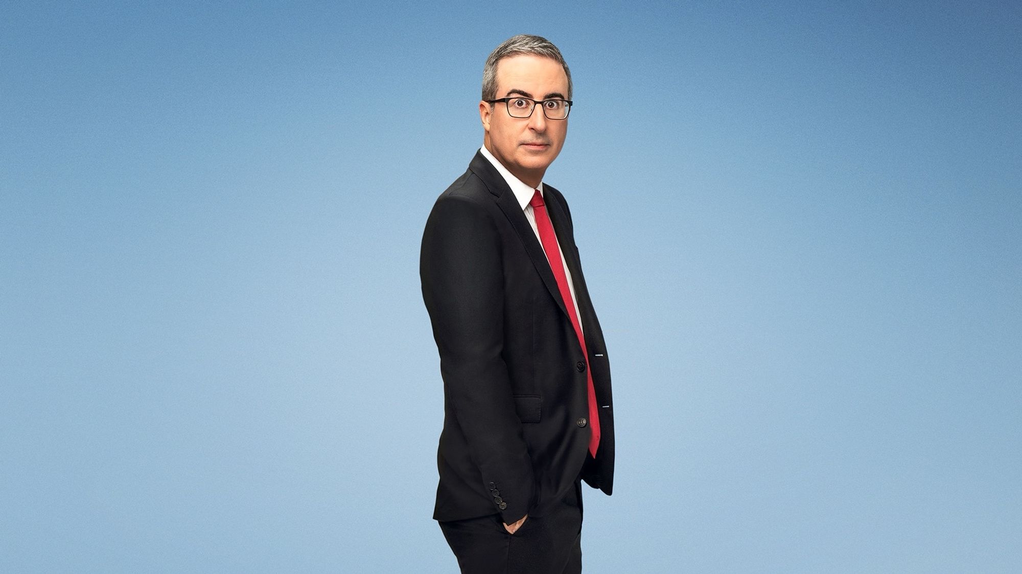 John Oliver looking at you (plain blueish background)