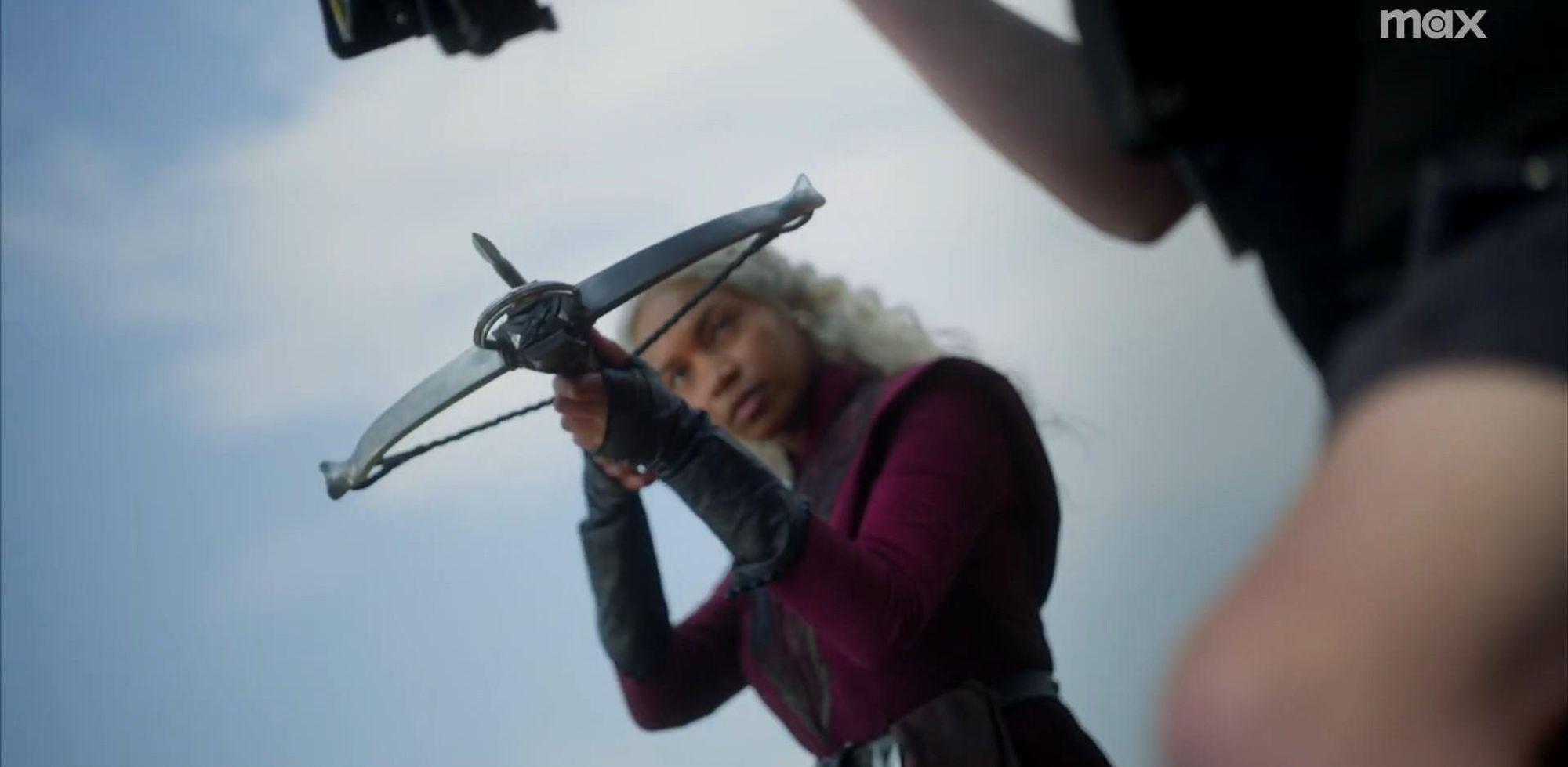 BHS photograph from season 2 of House of the dragon, featuring Baela Targaryen (Bethany Antonia), dressed in Targaryen black and red military garb, looking stern and pointing a black crossbow at someone offscreen.