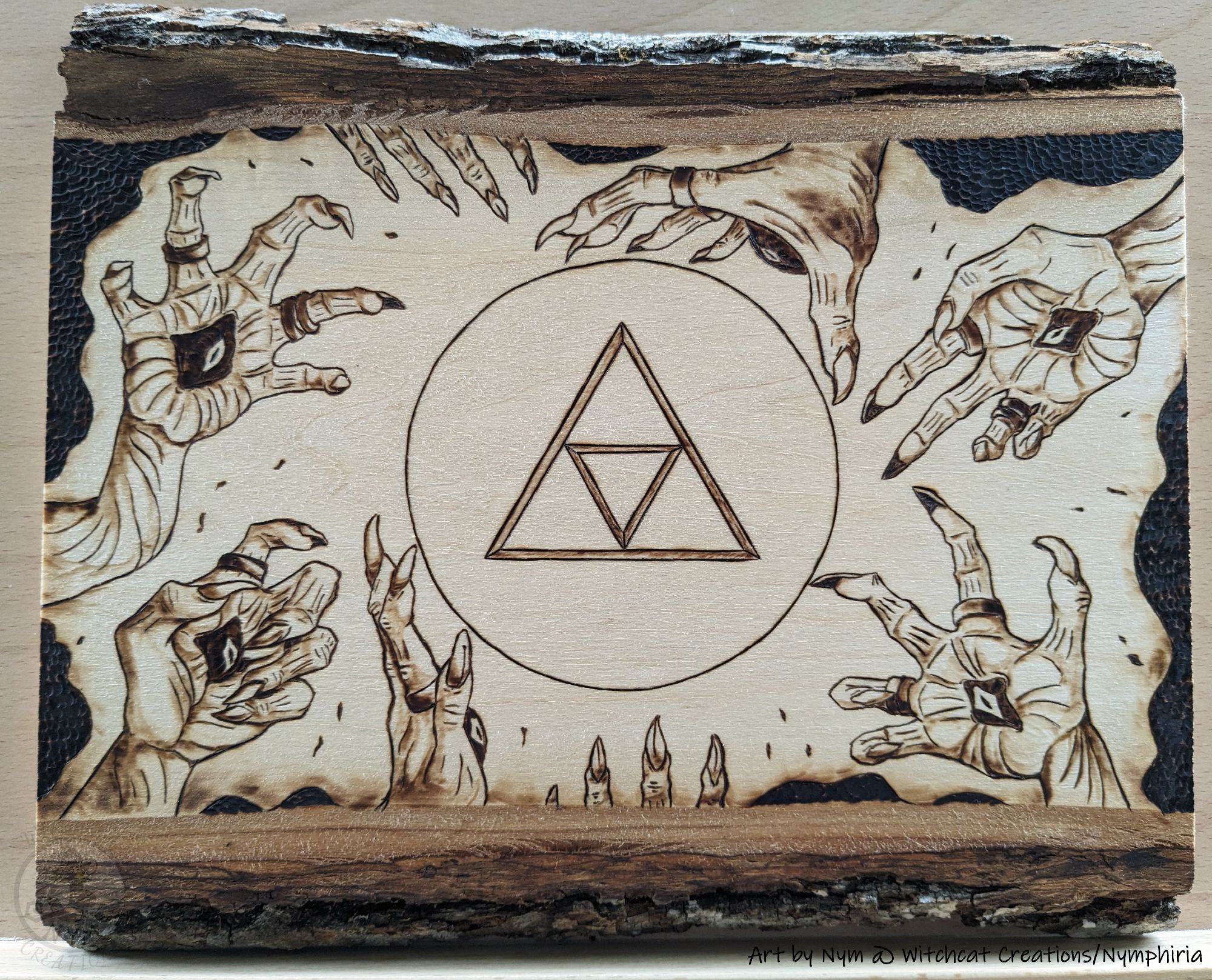 a photo of a pyrography piece with a triforce holding back gloomhands and darkness with radiant light